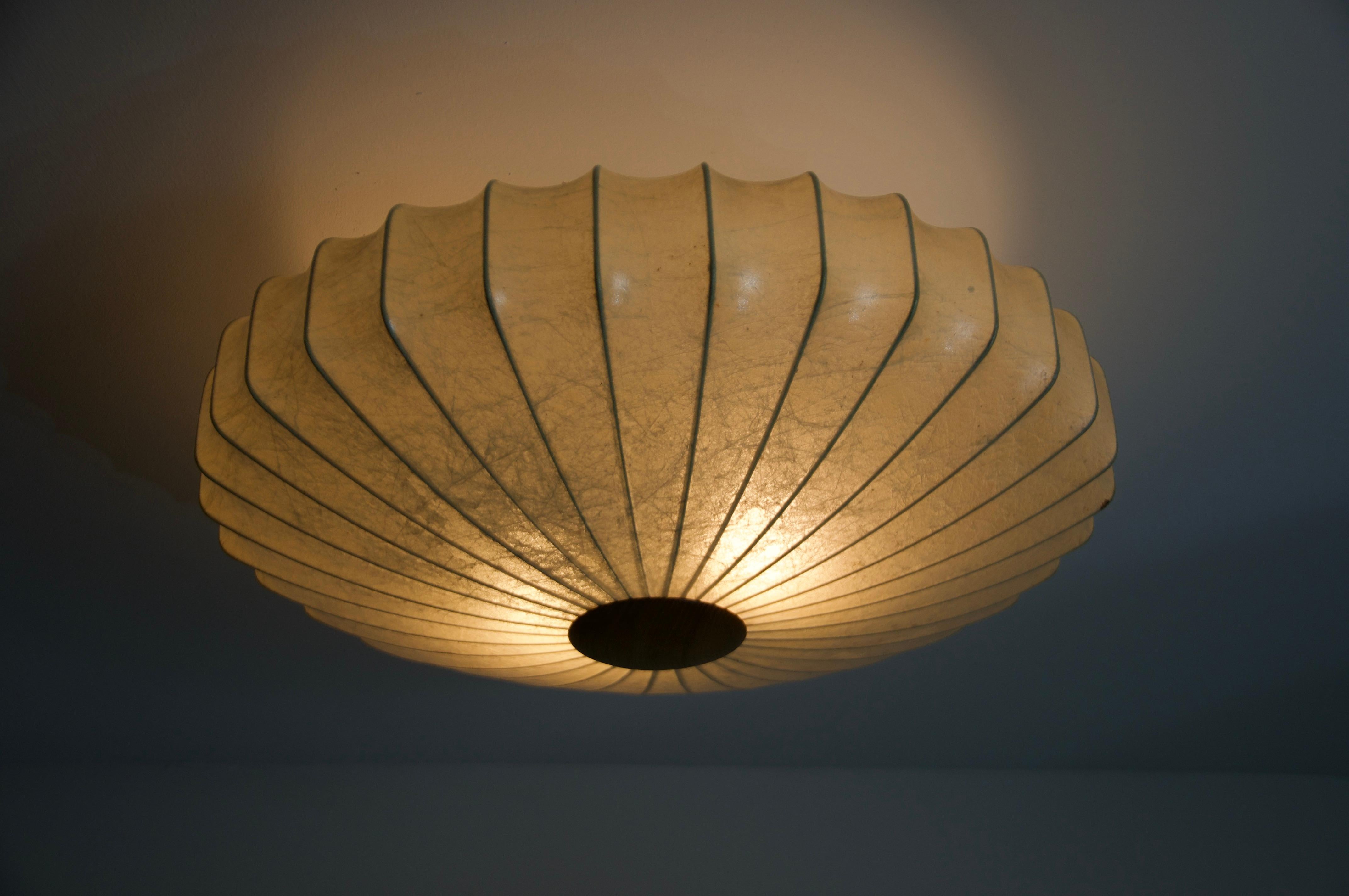 Cet élégant plafonnier cocon des années 1960 est un élément phare du design intemporel qui confère une atmosphère chaleureuse et élégante à n'importe quel espace. Le revêtement en forme de cocon, de forme organique, permet une diffusion douce de la