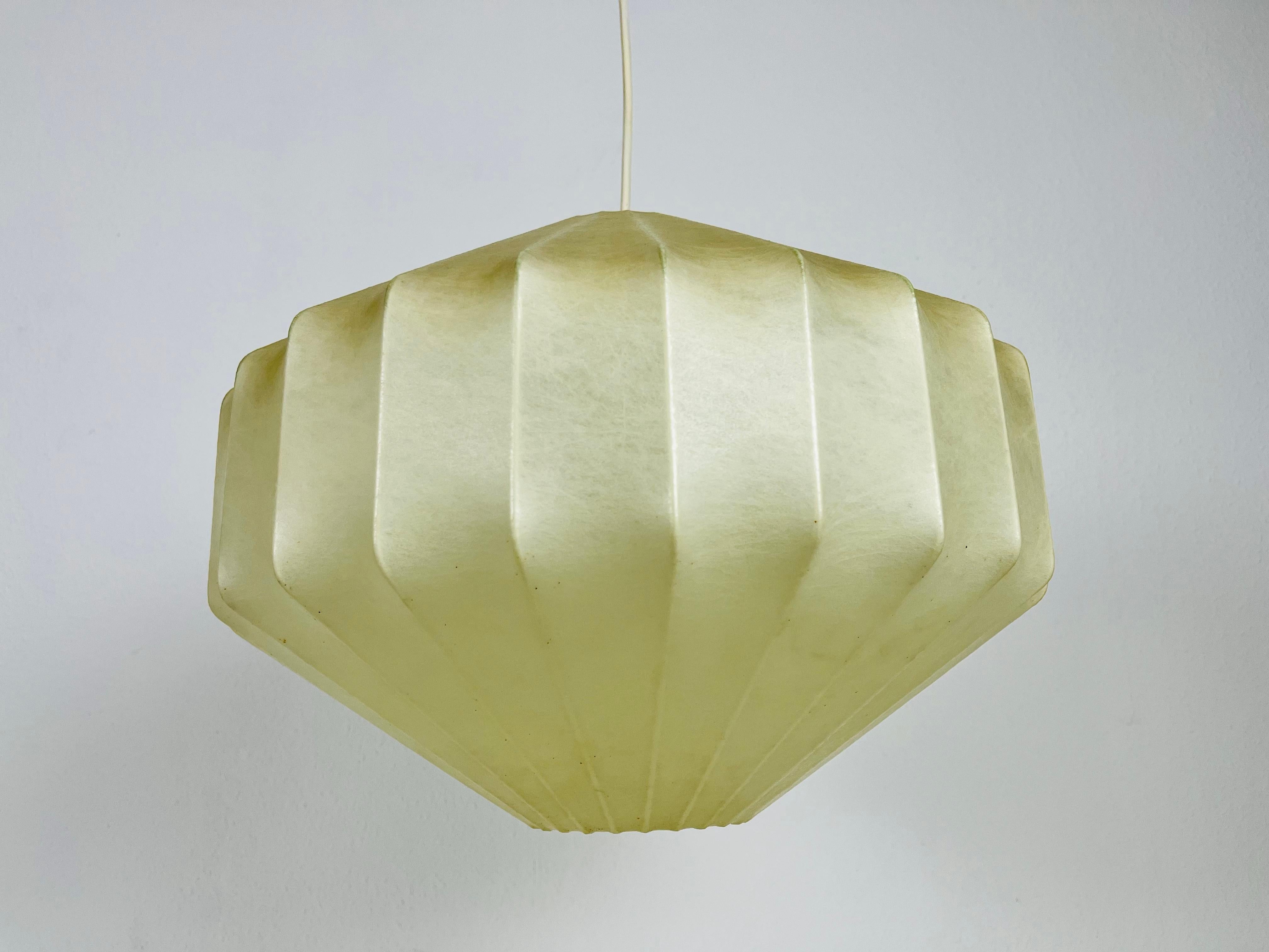 Lampe pendante cocon en losange fabriquée en Italie dans les années 1960. La lampe suspendue présente un design similaire aux luminaires réalisés par Achille Castiglioni. L'abat-jour est en résine d'origine et a une forme de losange.

Mesures