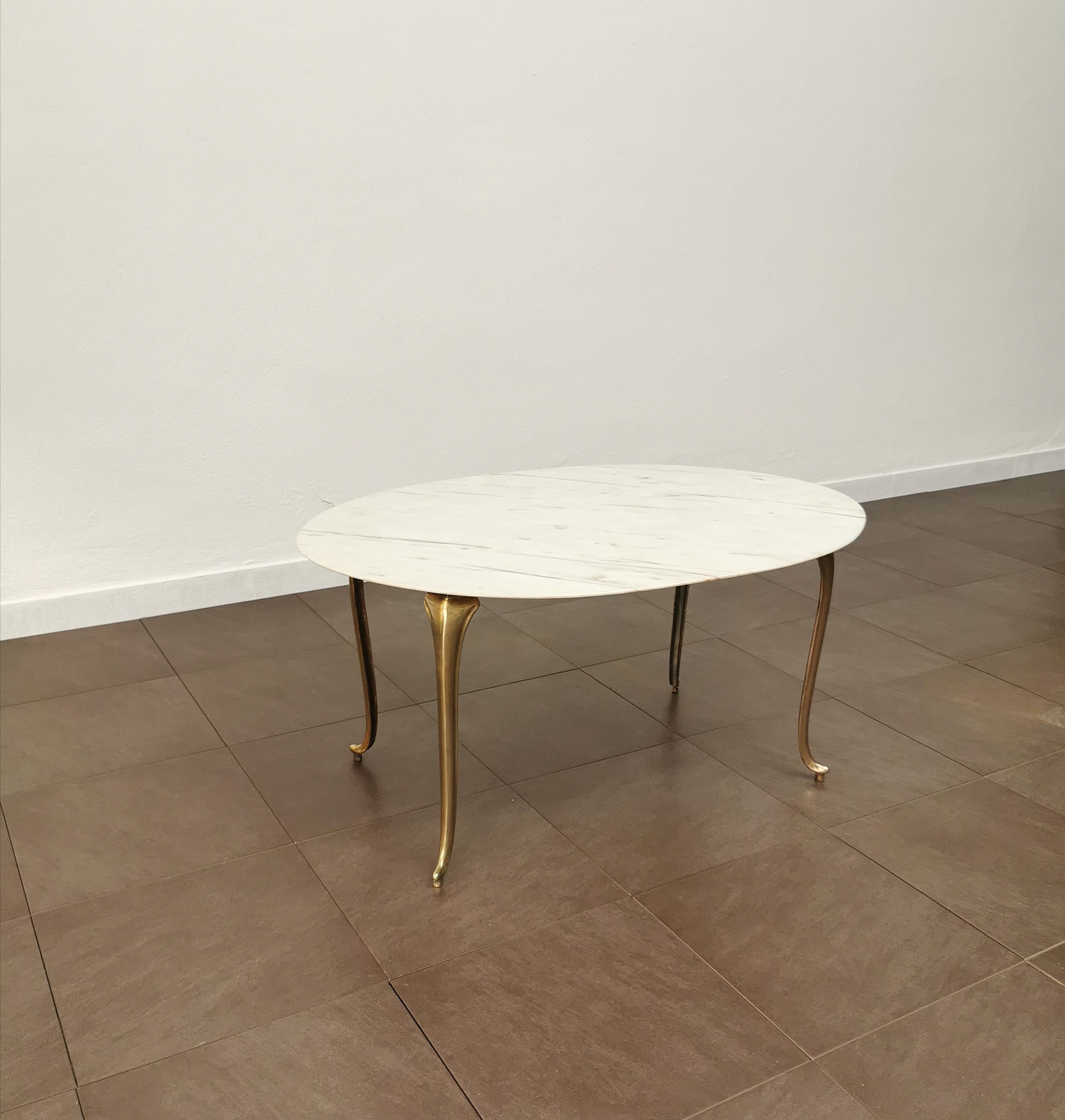 Coffee table made in Italy in the 1950s. The coffee table was made with a 4-legged brass structure with curvilinear shapes, where an oval-shaped top in white marble rests on top.