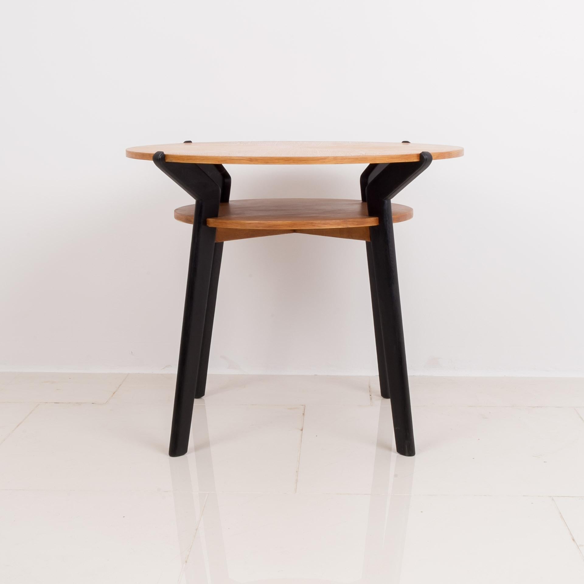 This beautiful coffee table was made in Czechoslovakia by famous manufacturer Interier Praha in 1950s. It features 4 black legs, a round table top and round shelf beneath. It is made of oak wood. The practical shelf under the table top allows for