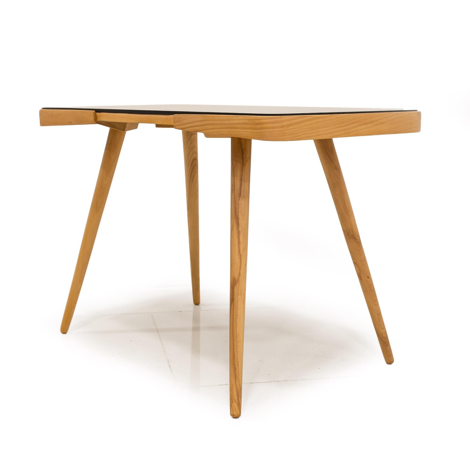This beautiful coffee table was made in the 1960s, designed by Jiri Jiroutek and was awarded at the Expo fair in 1958 in Brussels. It features 4 slender legs and top made of beech wood, covered with black glass. The piece is professionally renovated