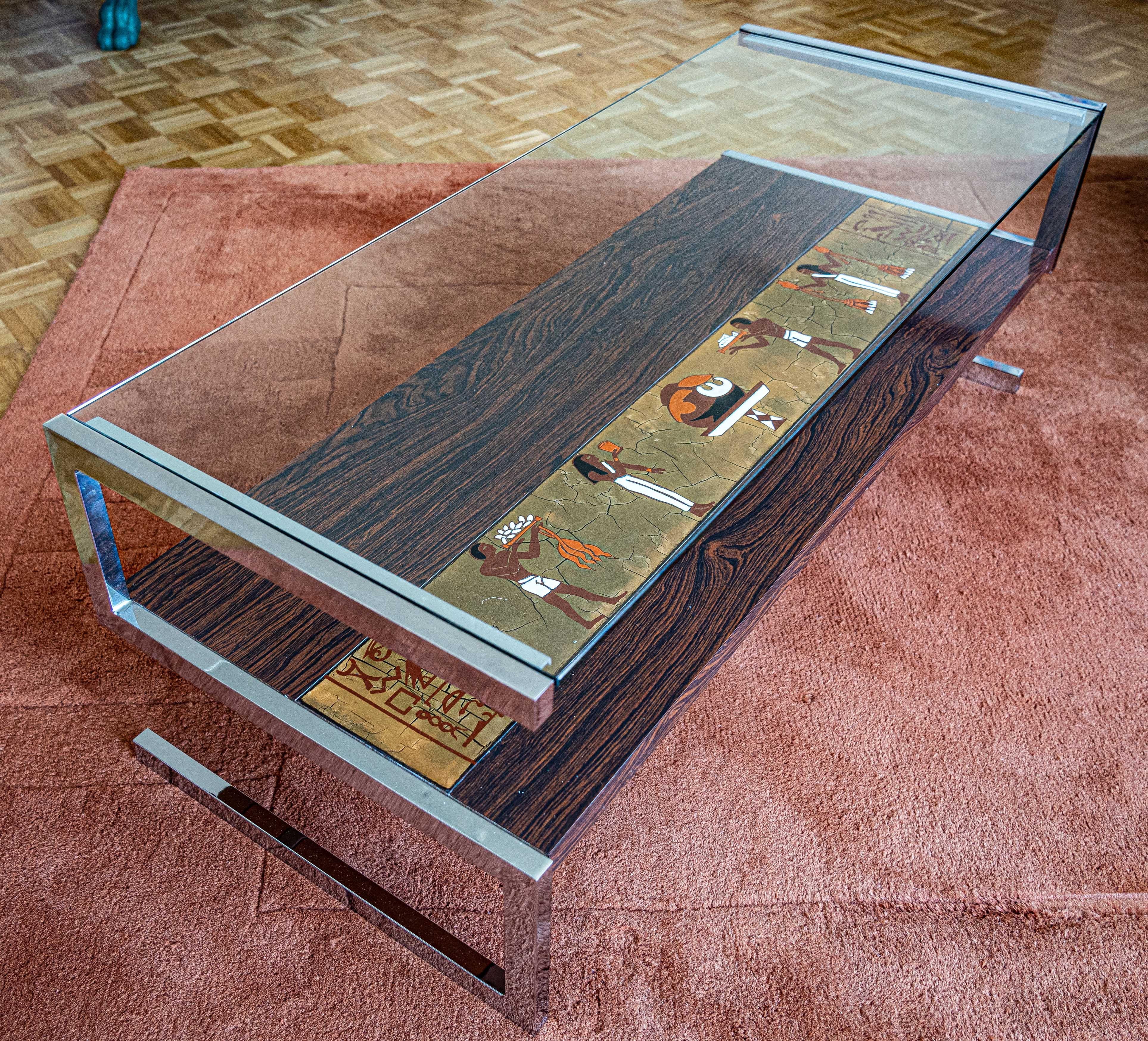 Midcentury coffee table in glass, steel and tiles with Egyptian motifs.
Refined pieces mixing cleverly a modern and contemporary design for the structure and archaïque references with the theme of the tiles which makes this piece one of a kind.