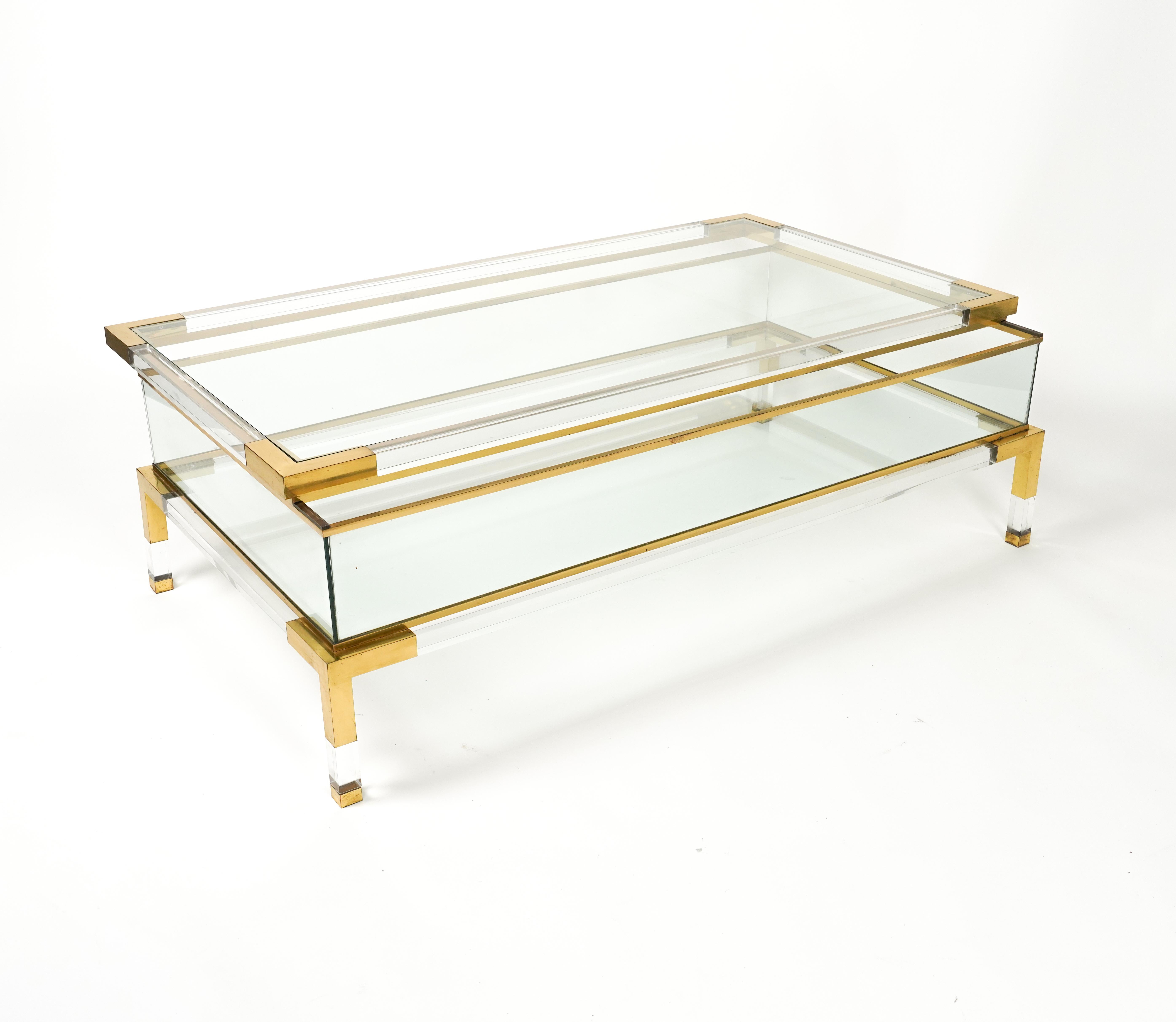 Beautiful mid-century rectangular coffee table in brass, lucite and glass with sliding top shelf. 

This fantastic piece was attributed to Maison Jansen in France during the 1970s.

This fantastic item is in good condition and has a double glazed