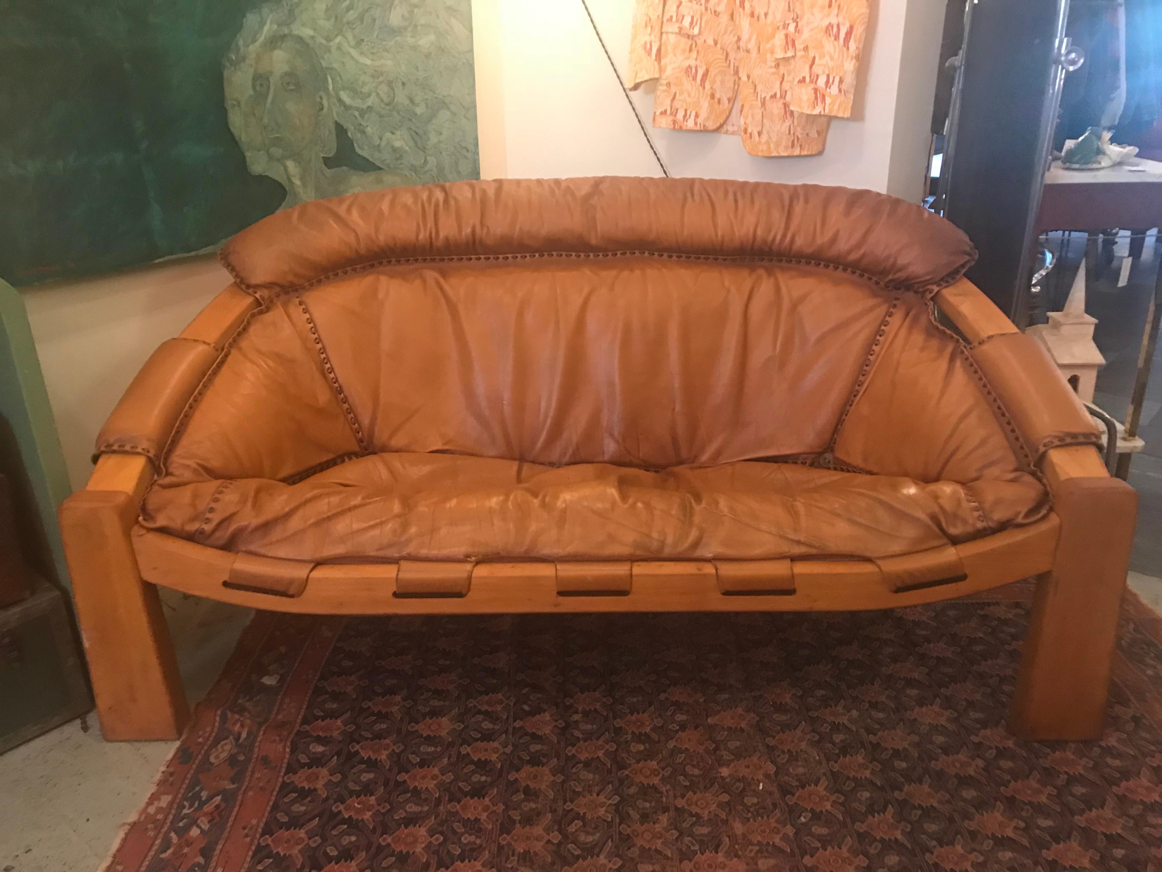 This is a rare and unique midcentury cognac leather sofa with dark brown stitching in the manner of Brazilian designer Percival Lafer.
