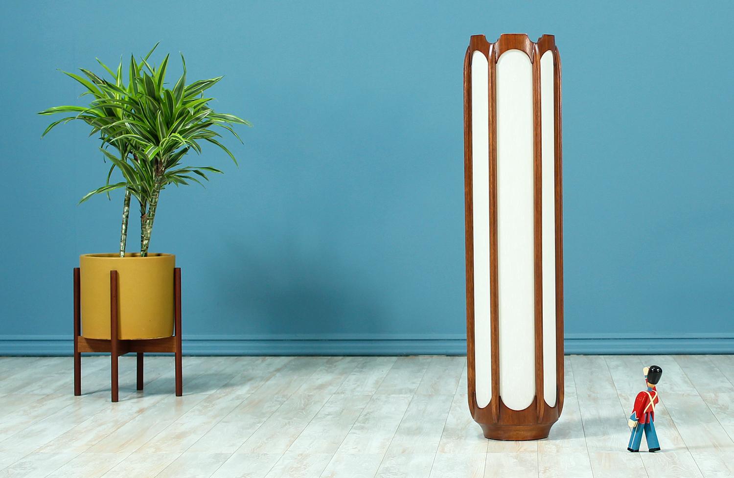 Gorgeous floor lamp manufactured by Modeline Lamp Co. in the United States circa 1960’s. Featuring a walnut wood frame composed of six carved columns that cover the vertical length of the cylindrical body and encase the new custom linen shade. This