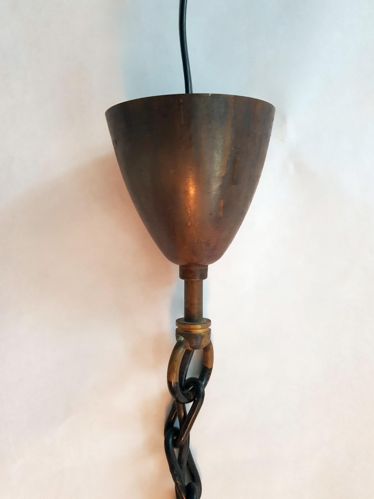 Danish design ceiling lamp in copper hanging in from a black chain.
