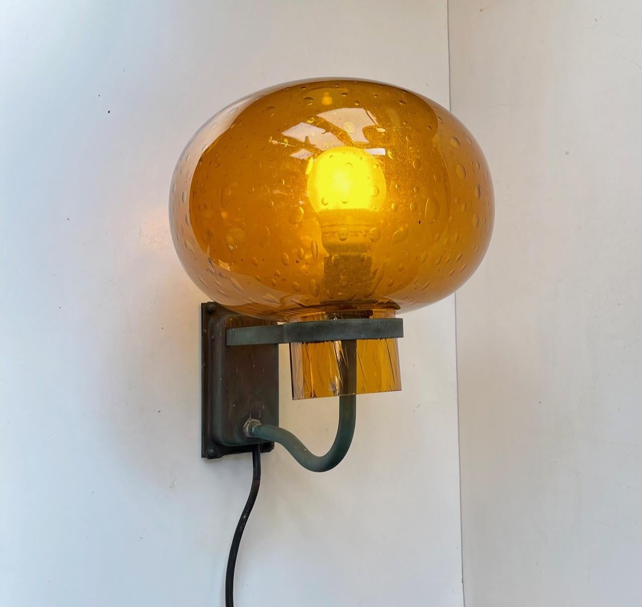 Outdoors wall light in naturally patinated/weathered copper and featuring a hand-blown freely resting shade in amber orange blister glass. It was made in Scandinavia during the 1950s or 60s possibly by ASEA/Gunnar Asplund. This style is definitely