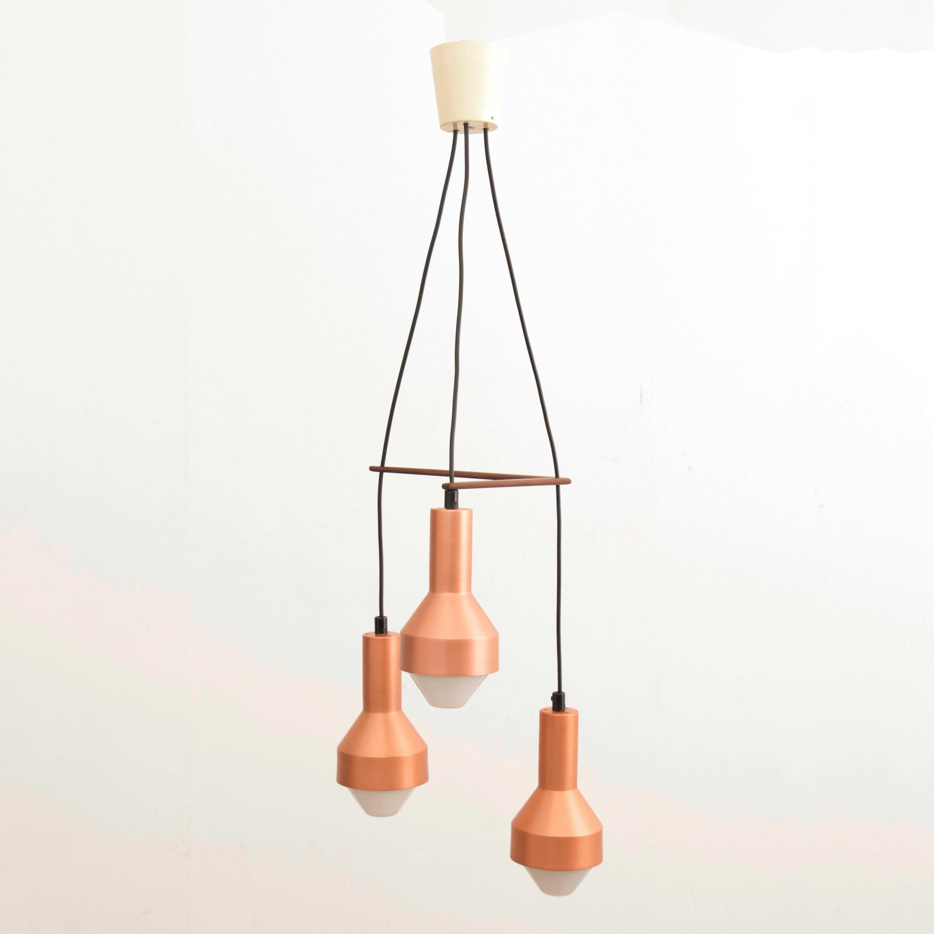A mid-century three tier pendant comprising Idman K2-133 copper anodised shades with a teak boomerang holder designed by Tapio Wirkkala. Wirkkala designed a collection of lights for Idman Oy, Finland, circa 1959 - 1961. 

Dimensions: 32 W x 32 D x