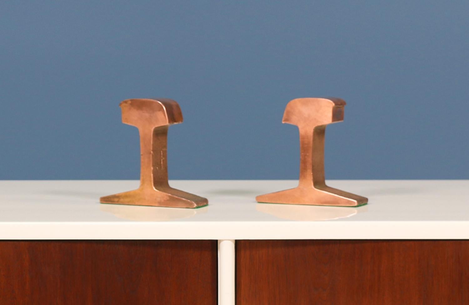 Midcentury copper railroad track bookends manufactured in the United States in the 1970s. Eclectic pair of bookends made of solid, patinated copper with beautiful warm hues will compliment your bookshelf perfectly. Both items show minimal wear from