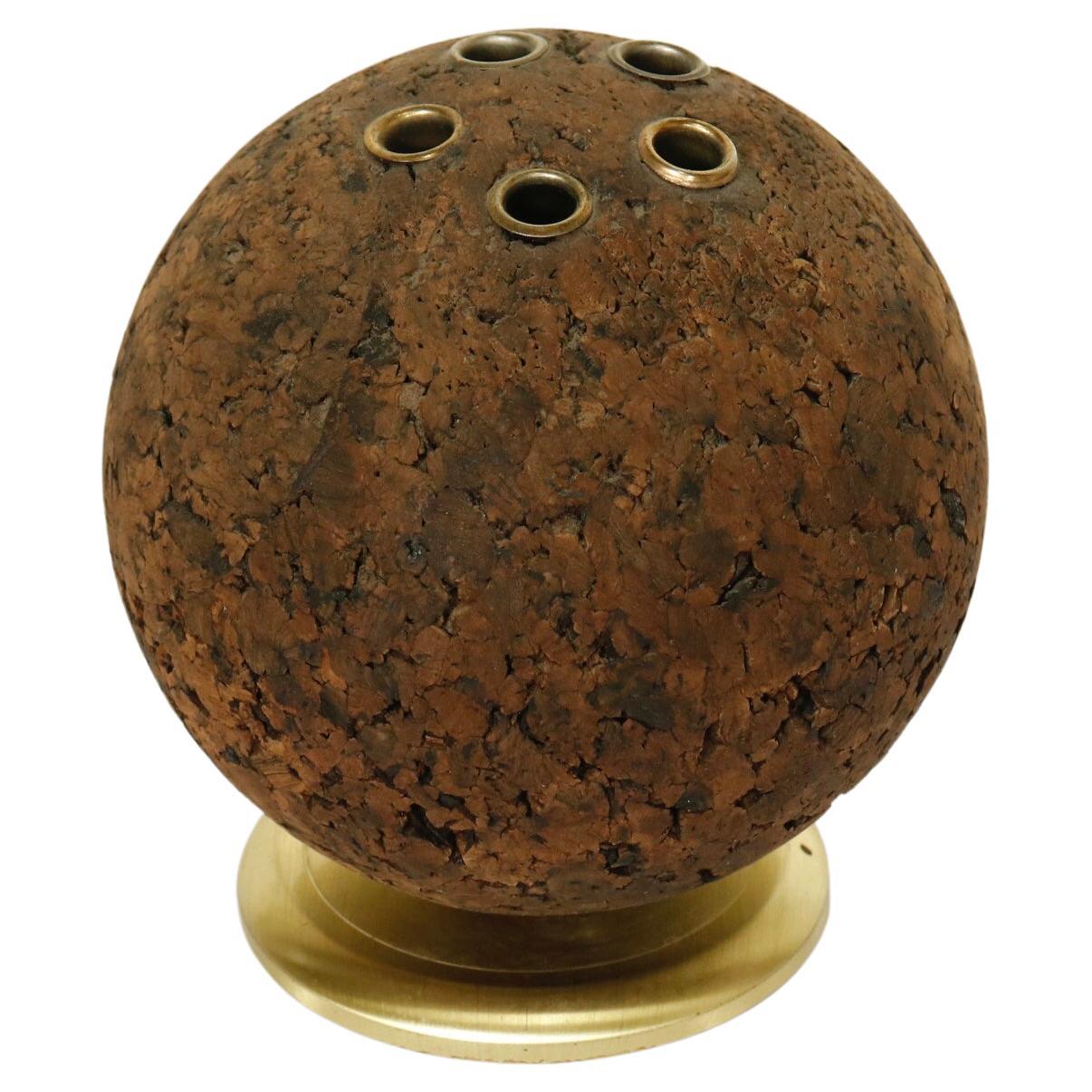 A spherical cork pen/pencil holder with brass swivel base. 

USA, circa 1960. 

Signed by maker.

Dimensions: 6” H x 5” W