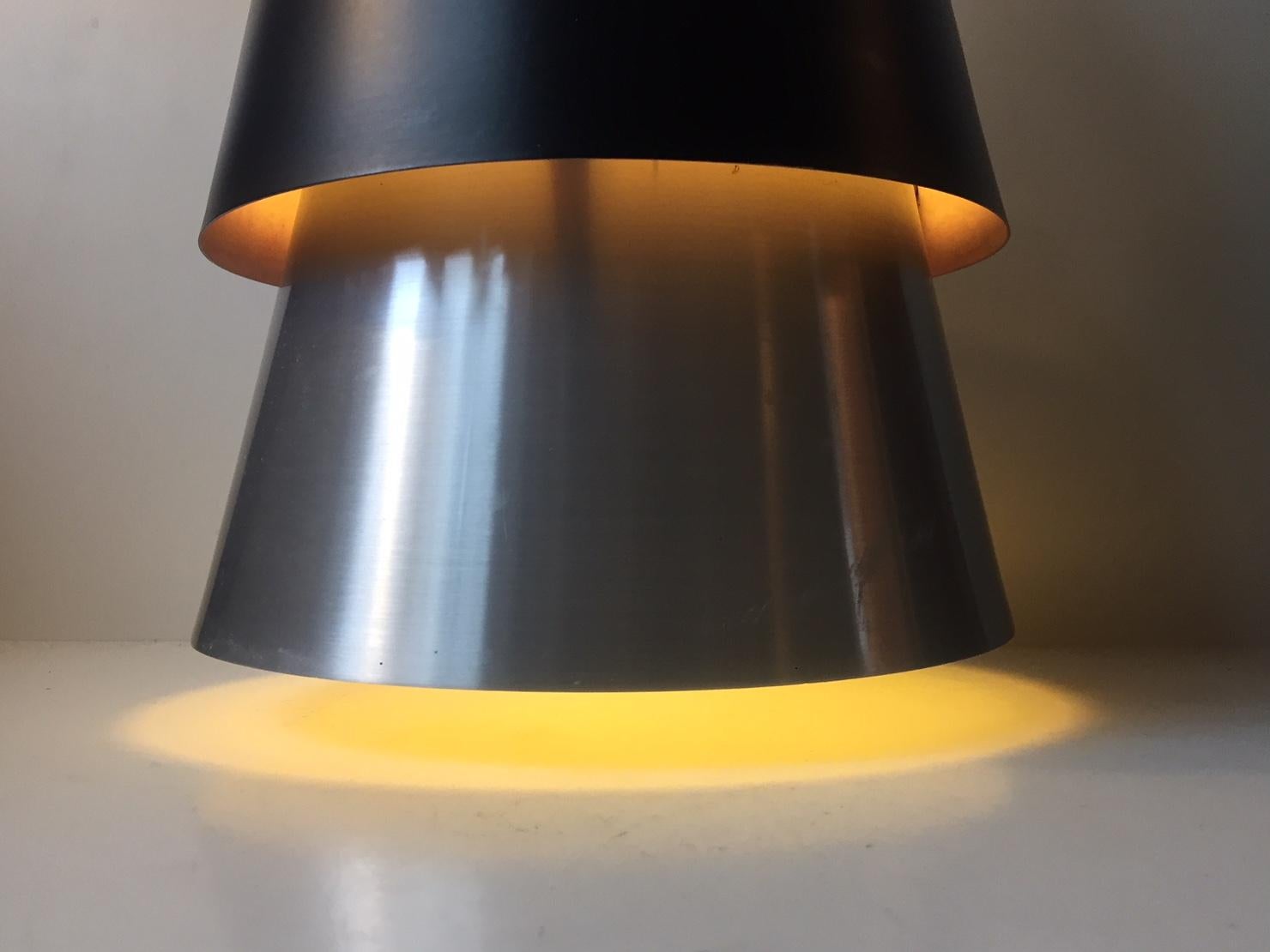 Large conical pendant lamp made from brushed aluminium set with a matte black shade. Its called Corona and was designed by Jo Hammerborg and manufactured by in the early 1960s.
 