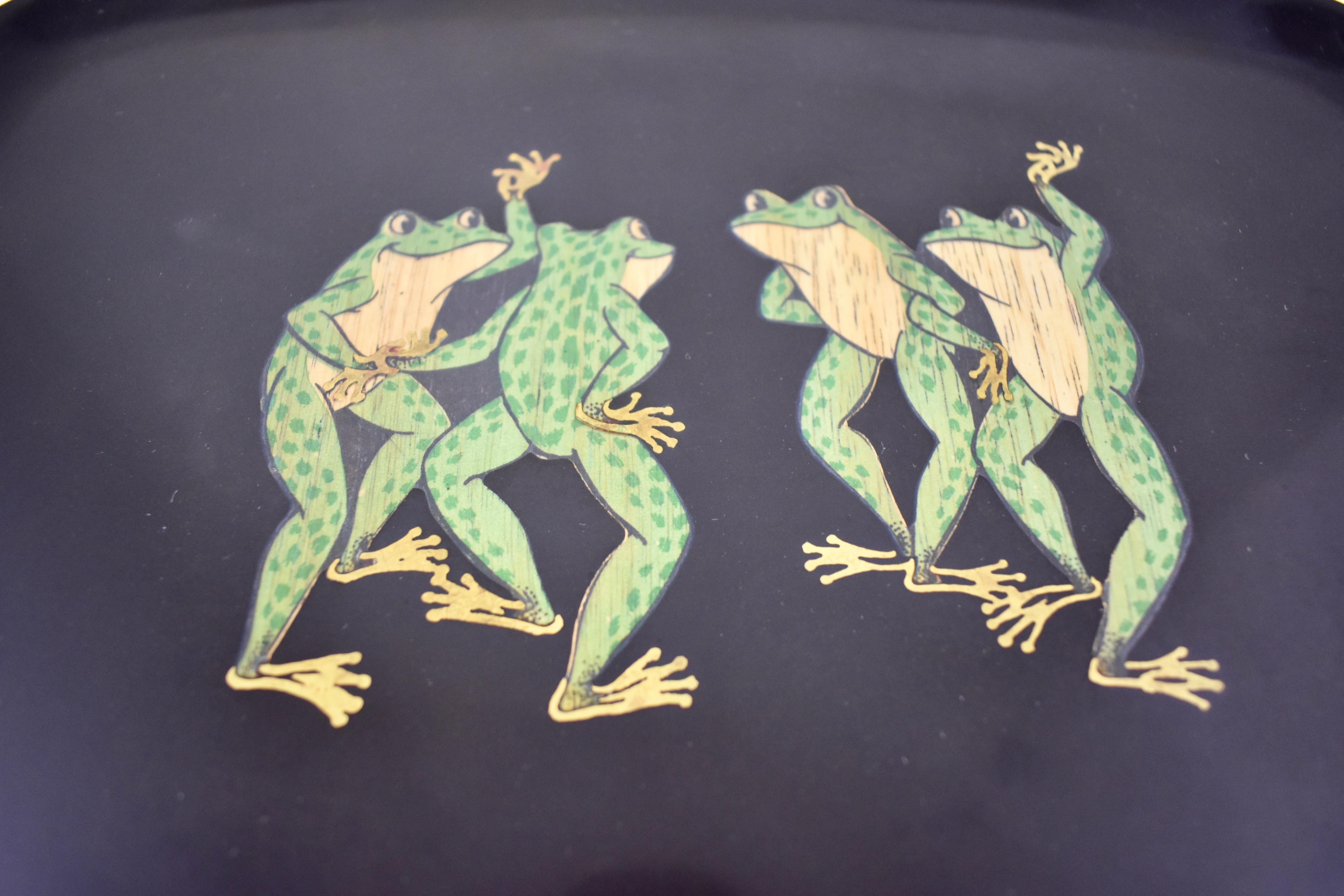 A midcentury serving tray by Couroc of Monterey, California, (1848-1998), The Dancing Frogs pattern, circa 1960s.

Made of a black resin called ‘Phenolic’ and hand inlaid with the image of four in green dyed wood with brass accents. Having the