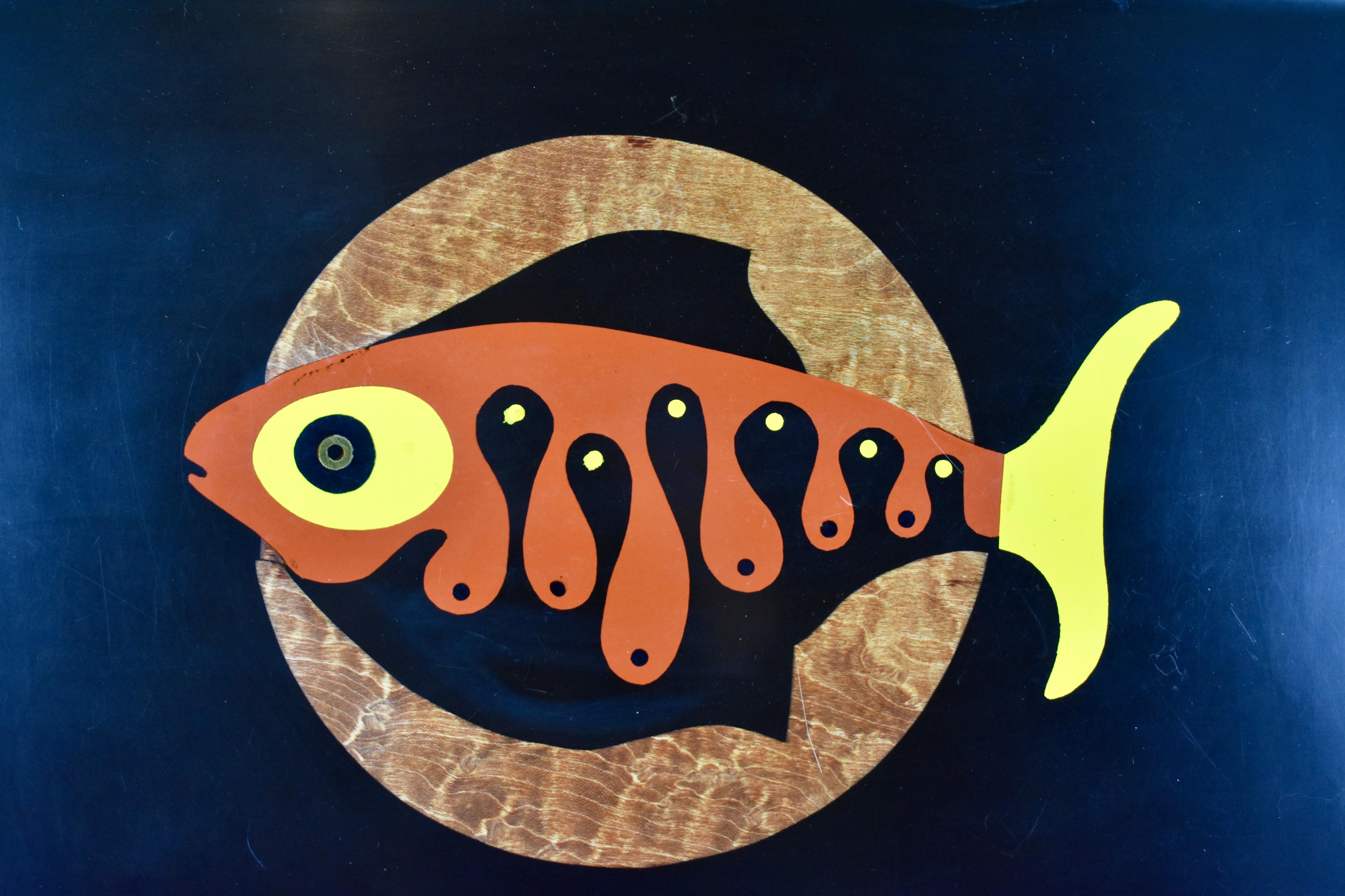 A Mid-Century Modern serving tray by Couroc of Monterey, California, (1948-1998) – A Fish theme, circa 1960s.

Made of a black resin called ‘Phenolic’ and hand inlaid with the image of a stylized swimming fish. The inlay consists of brass and