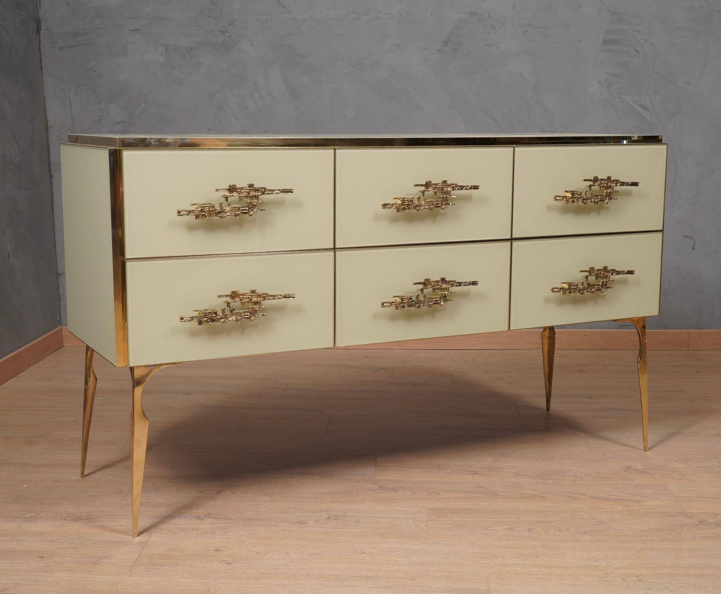 Very elegant Italian chest of drawers covered entirely in glass and brass, features its legs in a micro fusions of brass, very precious workmanship.

The chest of drawers is composed of a well-designed wooden structure with three upper and three