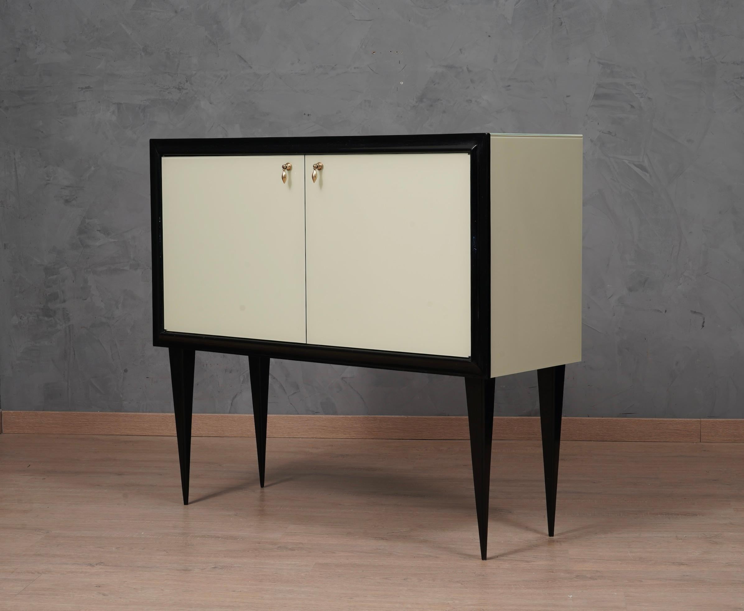 A unique sideboard of its kind for originality and for the choice of materials. Simple but refined design, the inside is completely covered with small mirrors, a real miniature mosaic. Note the rich design of the doors, with smooth colored glass