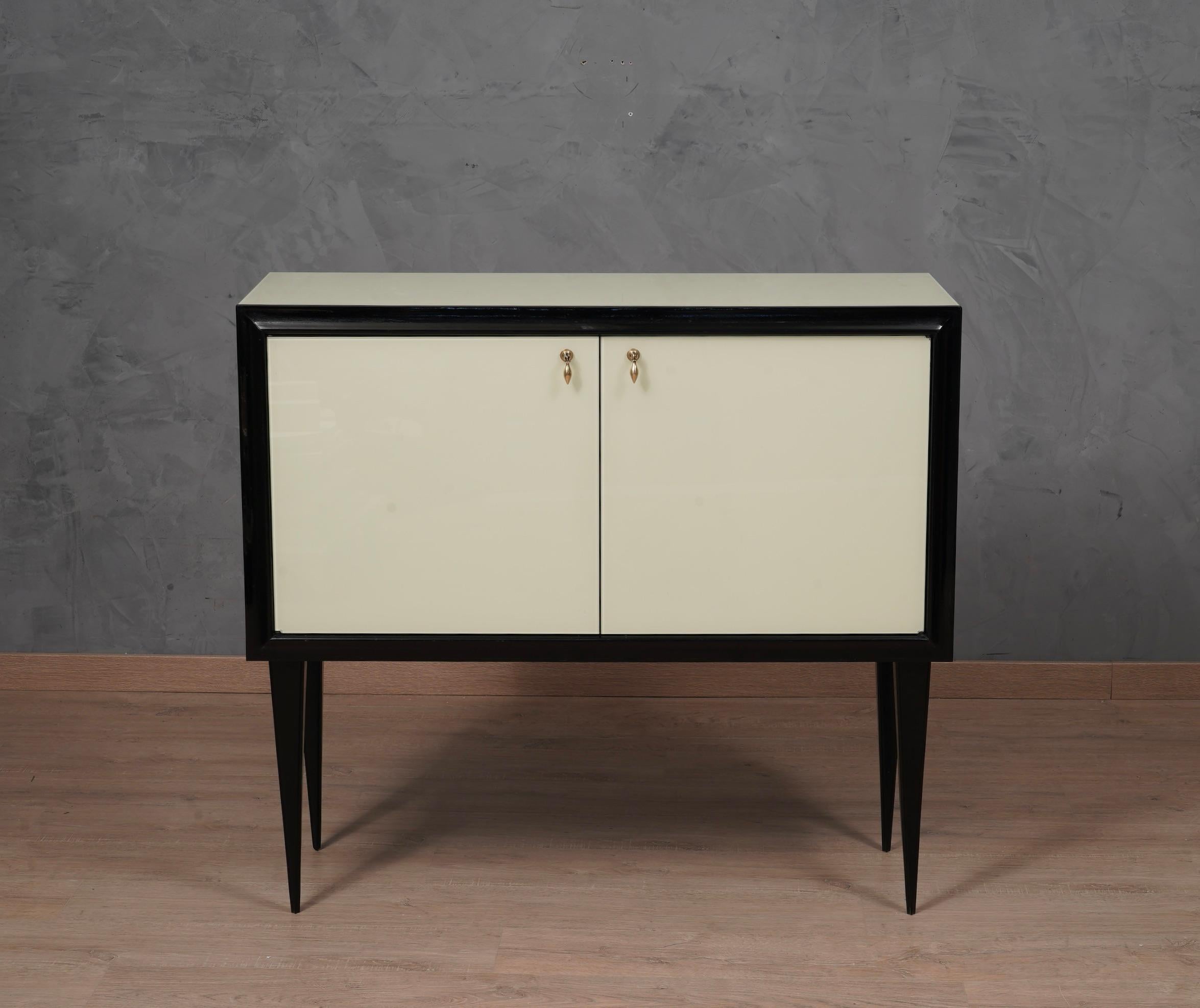 Una credenza unica nel suo genere per originalità e per la scelta dei materiali. Dal design semplice ma raffinato, l'interno è completamente ricoperto di piccoli specchi, un vero e proprio mosaico in miniatura. Nota il ricco design delle ante, con