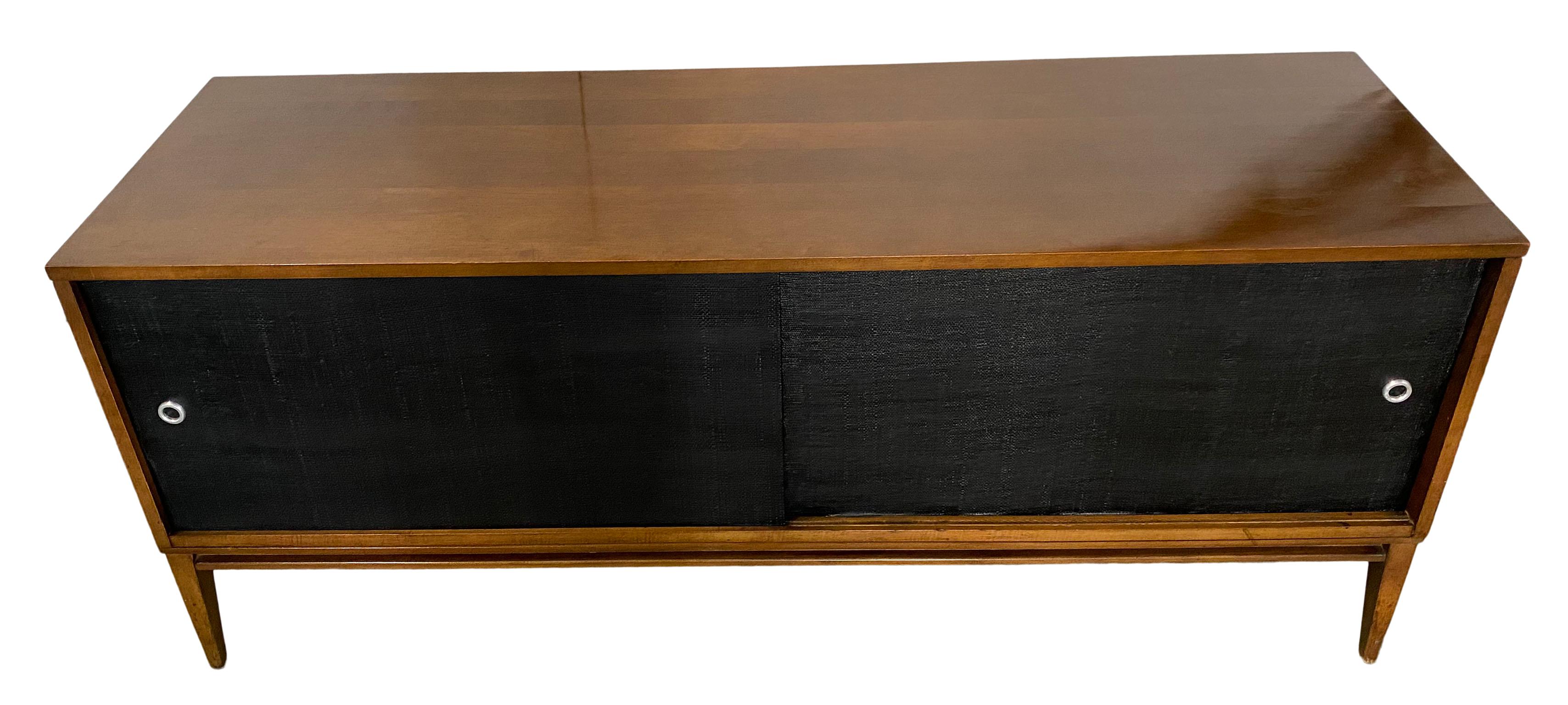 Beautiful midcentury low credenza cabinet with sliding doors by Paul McCobb circa 1950 planner group #1513 has 2 adjustable shelves with pins - solid maple construction has a dark walnut finish. All original Black cloth sliding front doors with