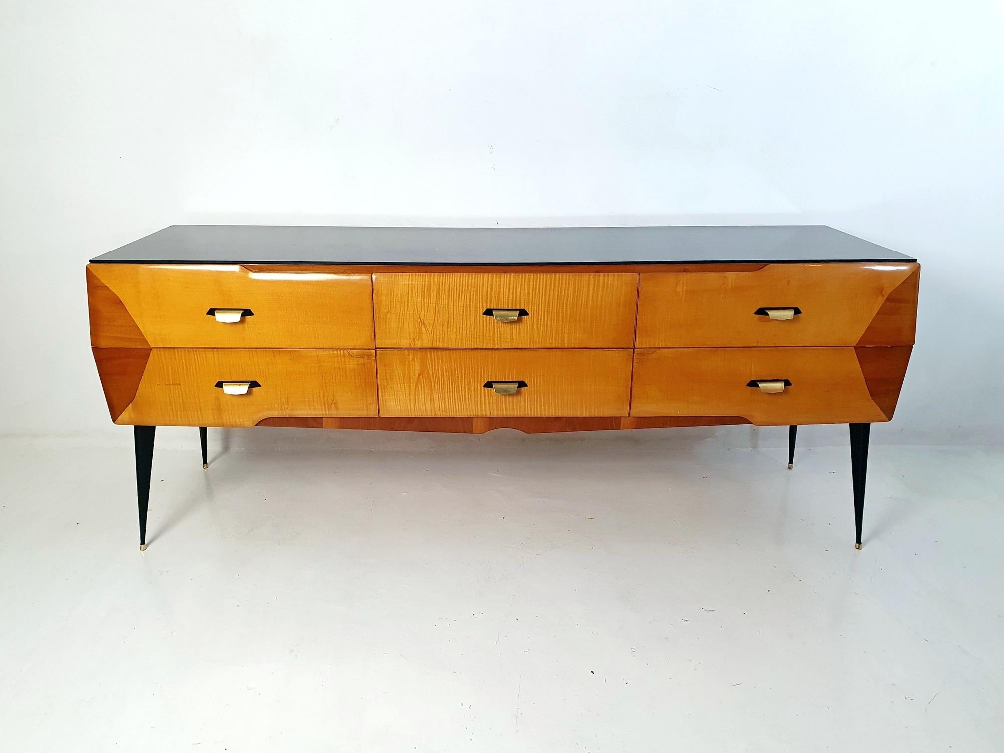 This Italian midcentury credenza, reminiscent of the iconic style of Gio Ponti, exudes innovation and sophistication. Crafted with lightweight materials, the piece showcases four beveled drawers made from maple and walnut. In combination with it's