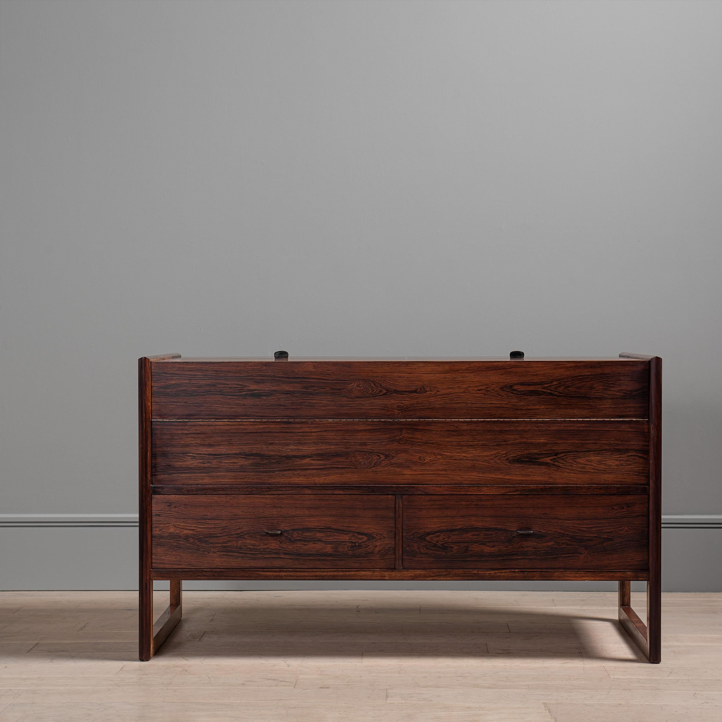 A highly unusual Scandinavian modernist piece of furniture. Flip top upper section with drawers below. Small leather inset handles. Sled design leg frame. Lovely design and a very practical storage piece. Great design and extremely well made with