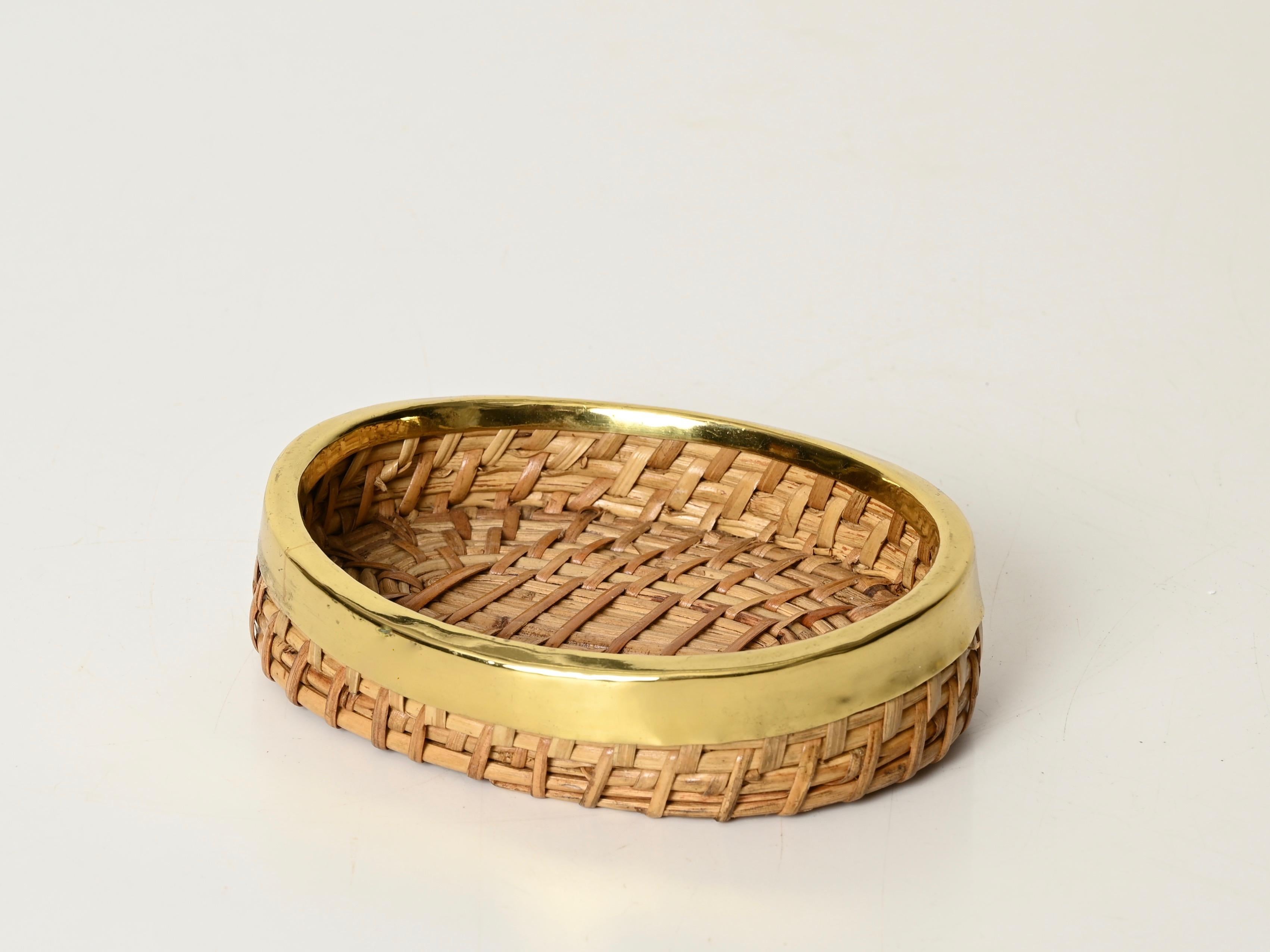 Maravilloso cuenco decorativo o vide-poche de mediados de siglo totalmente realizado en ratán curvado, mimbre tejido a mano y latón pulido. Este elegante cuenco de estilo Riviera francesa fue diseñado en Italia durante la década de 1970 siguiendo
