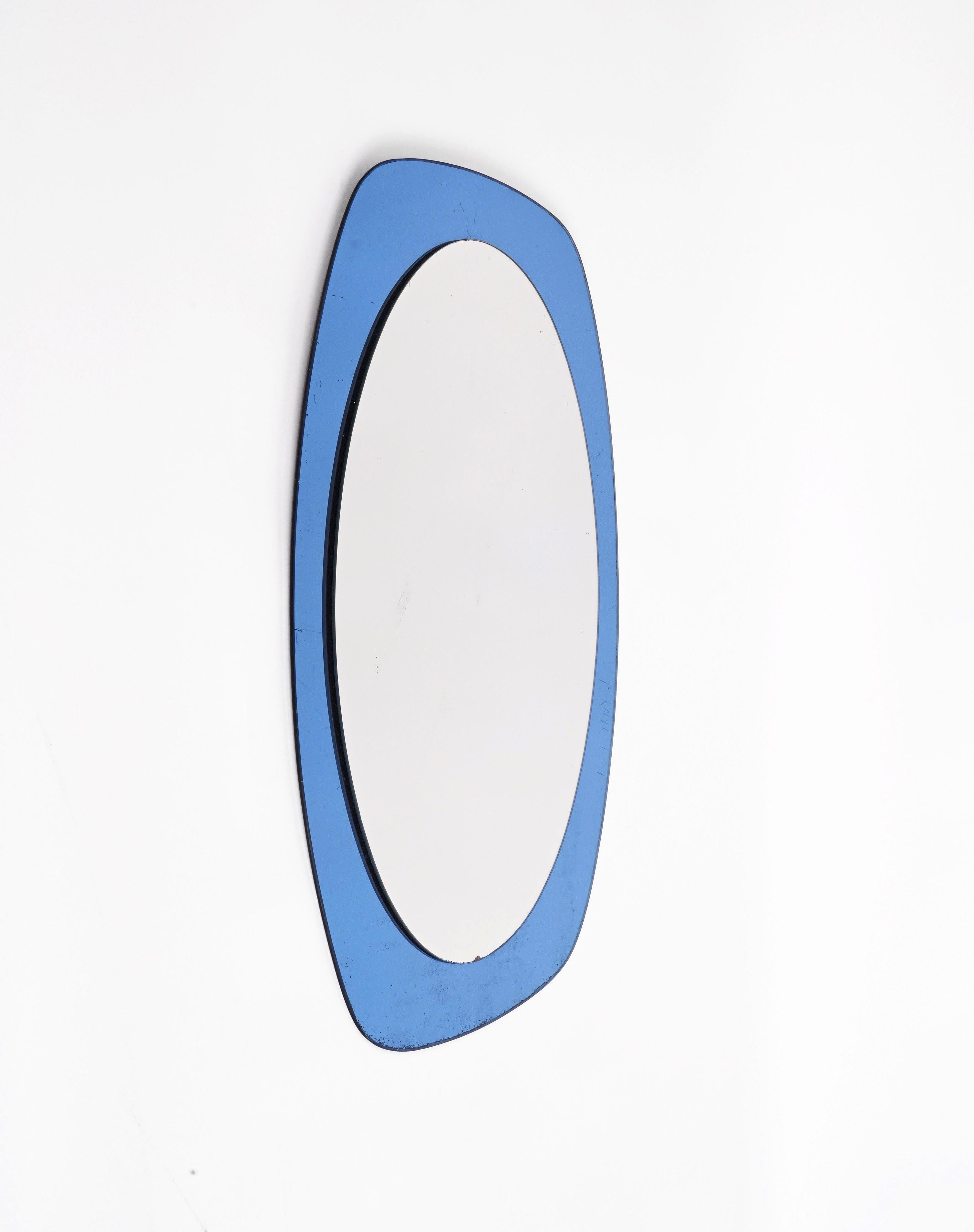 Amazing oval double-levelled midcentury mirror with a blue glass frame. This wonderful piece was produced in Italy during the 1960s and it is attributed to Crystal Art.

In its essential and pure mid-century design and lines, this marvellous item