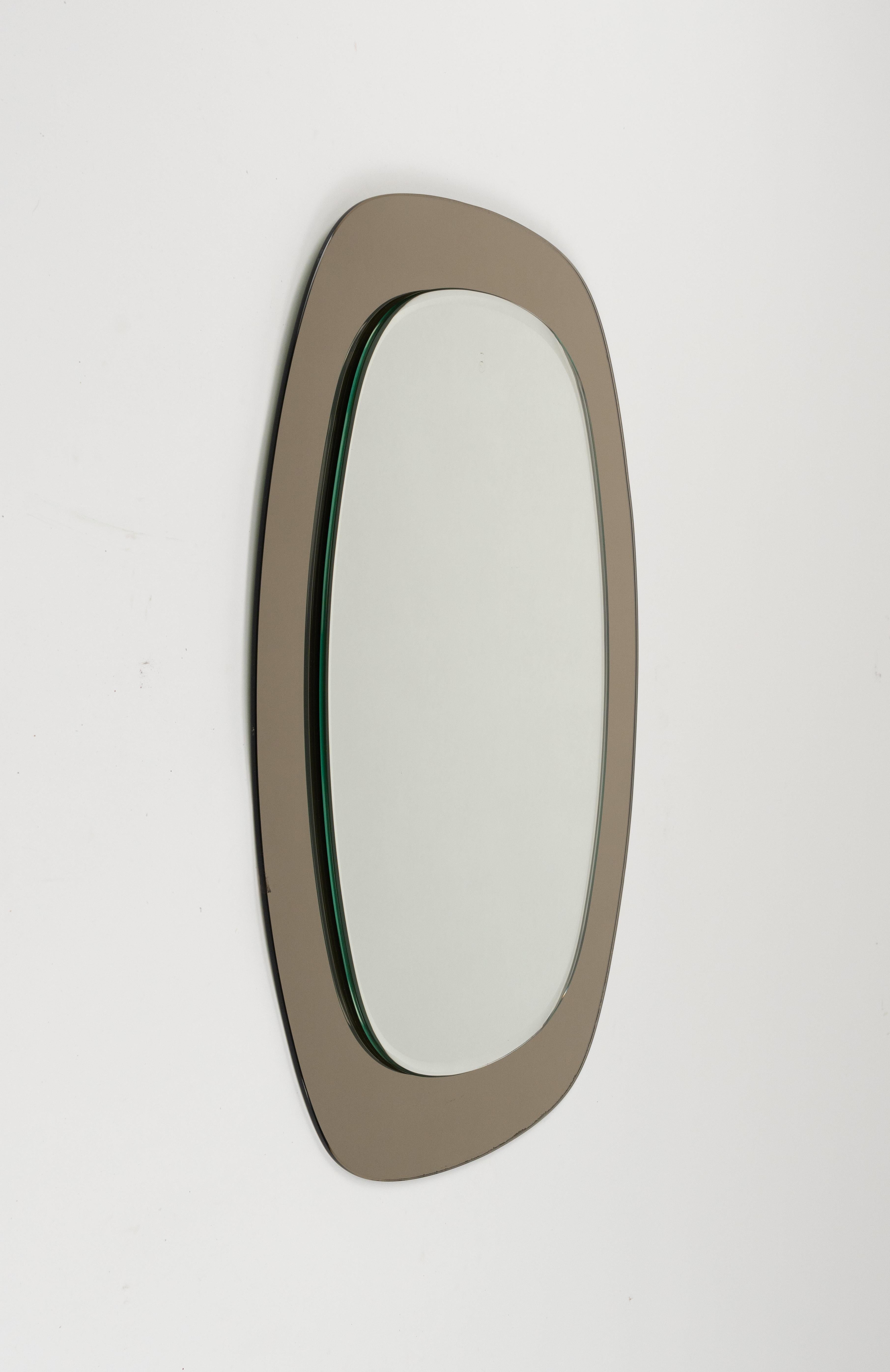 Midcentury beautiful double-level oval wall mirror with a smoked glass frame attributed to Cristal Art.   

Made in Italy in the 1960s.  

The mirror, original of the period, shows small signs of discolouration.