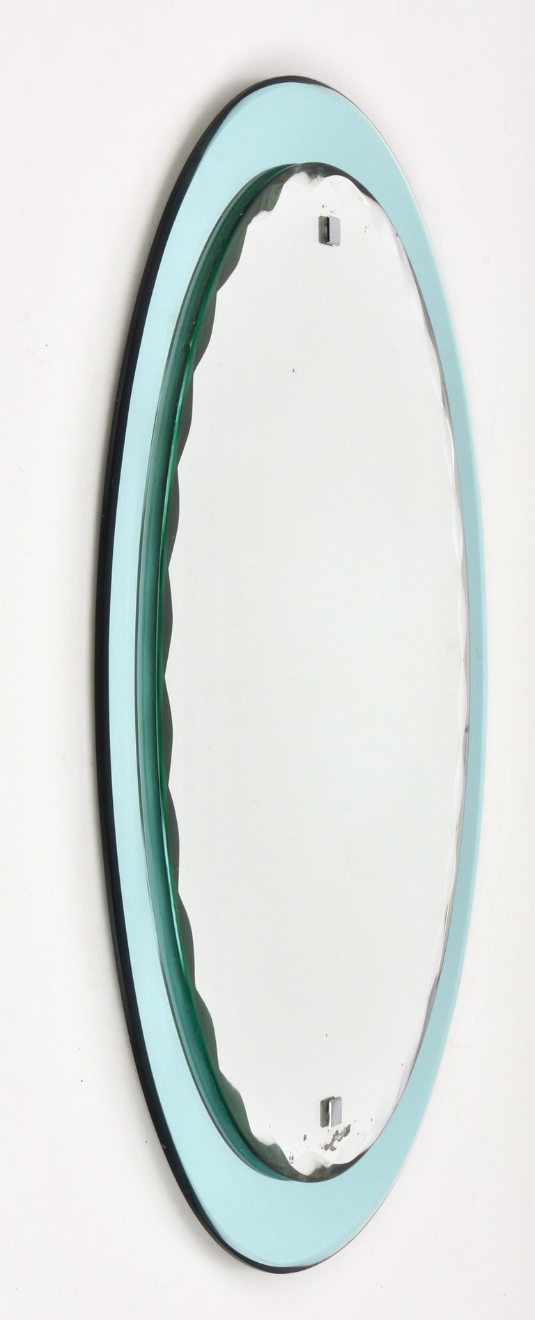 Beautiful midcentury mirror with light turquoise frame and oval graven mirror. This Italian mirror is in the style of Cristal Arte and it was made in Italy in the 1960s.

This piece is an example of excellent Italian manufacture, with the back of