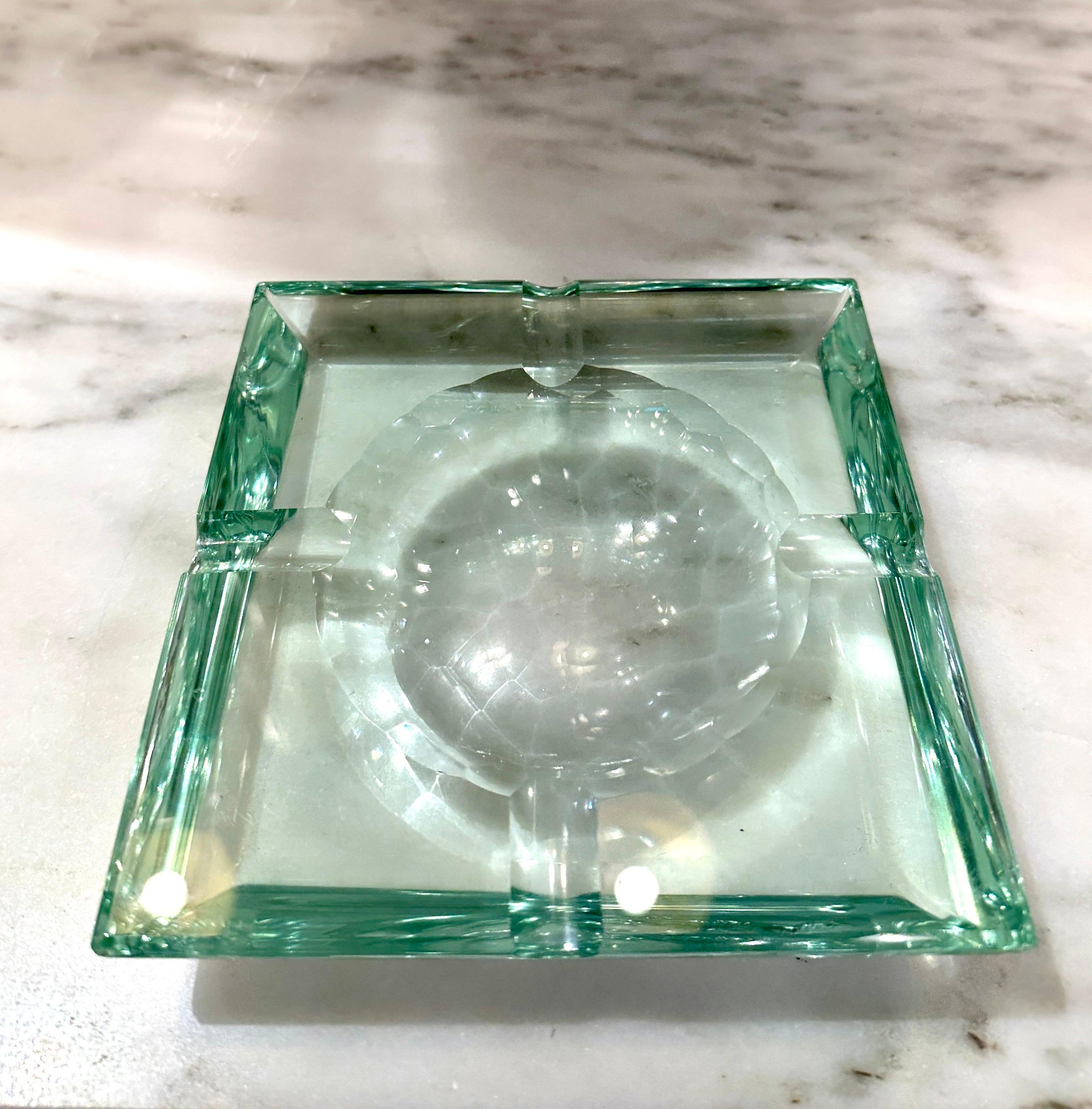 Indulge in the elegance of this exquisite ashtray or Vide-Poche, crafted in Italy during the prestigious Fontana Arte's prime in the 1960s. The square-shaped design boasts a transparent crystal glass with a subtle green hue.

This versatile piece