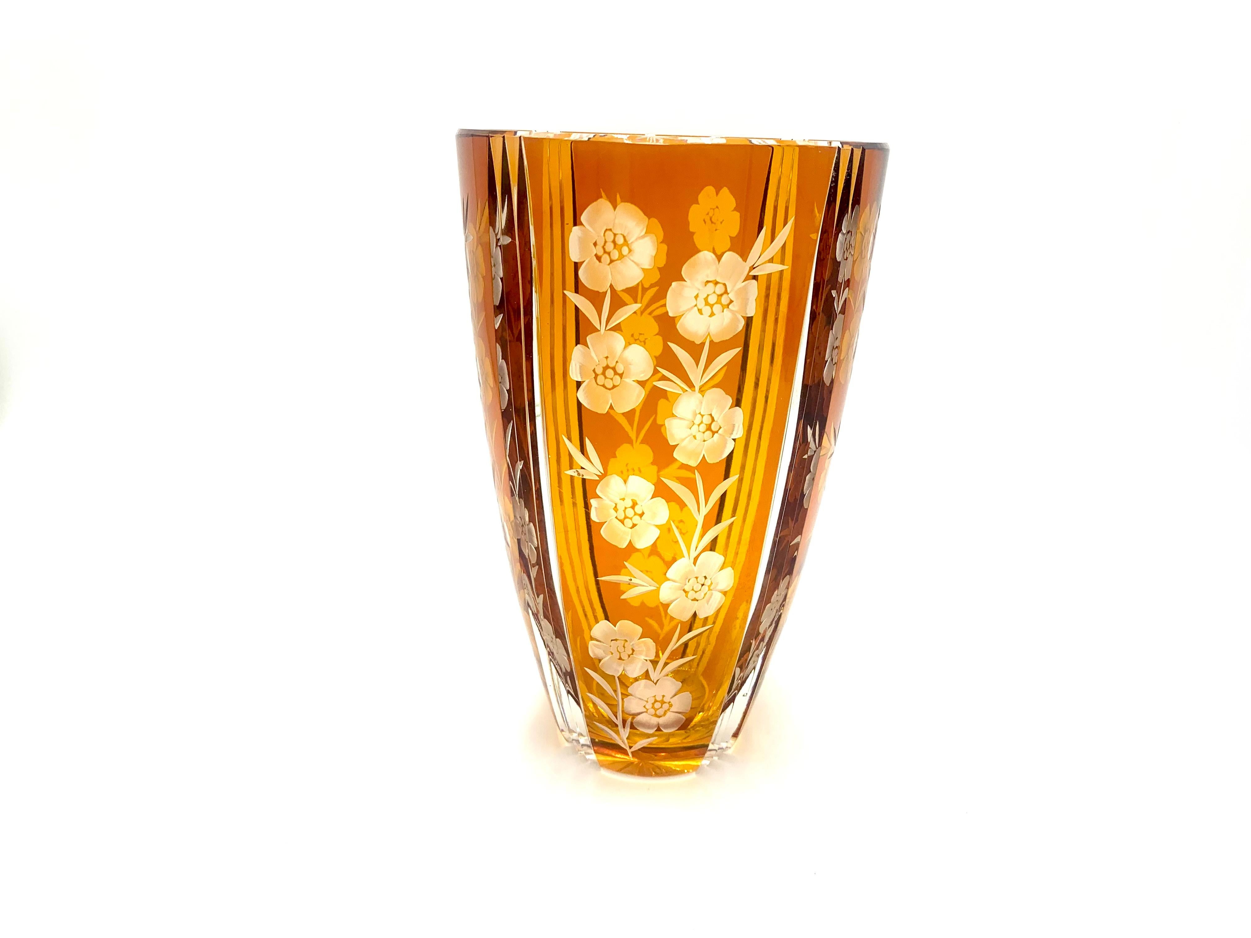 An amber colored crystal vase with a floral motif.

Manufactured in the mid-twentieth century by Huta Józefina.

Measures: height 23cm, diameter of the outlet 14cm.
