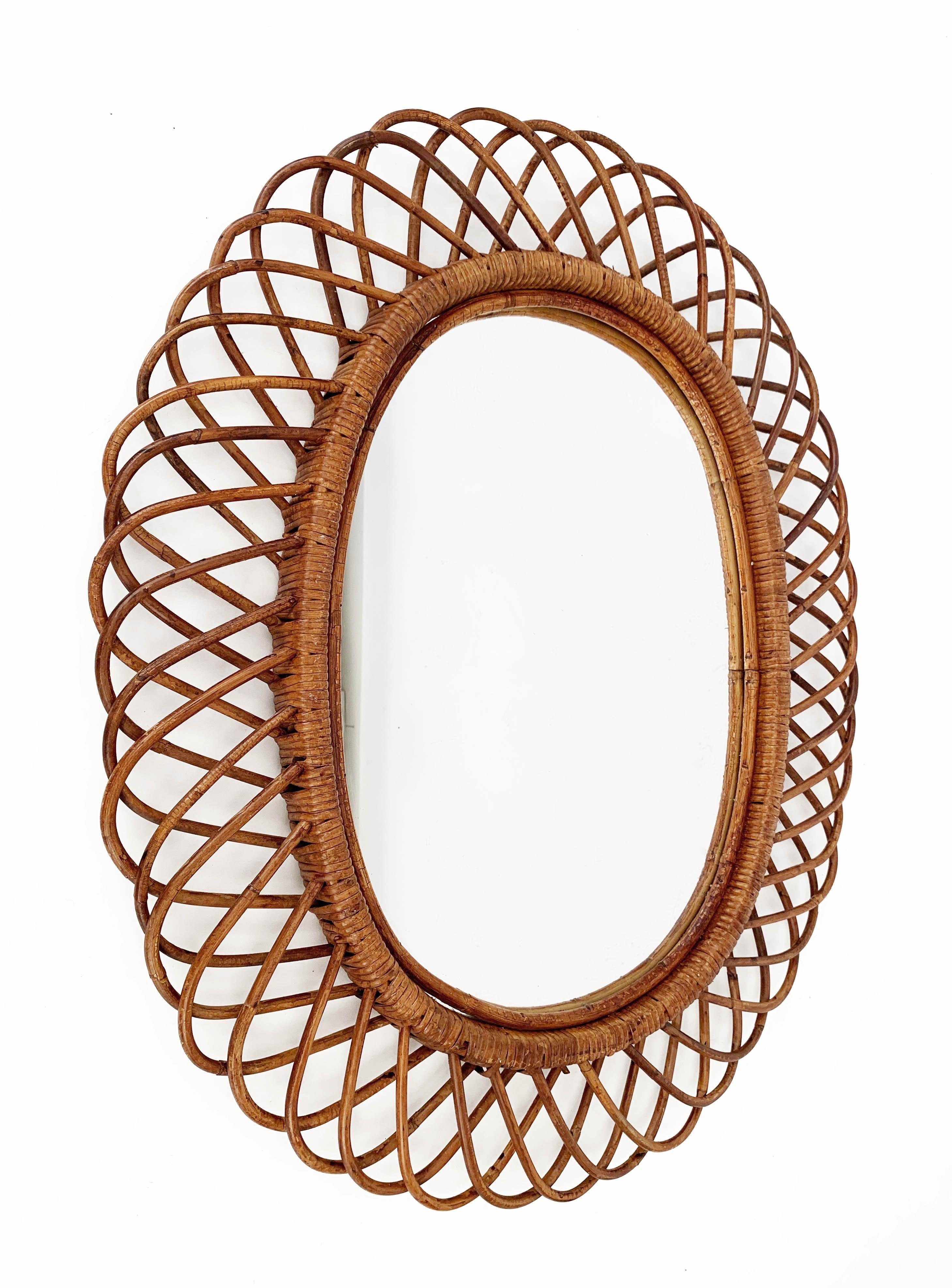 Amazing midcentury French Riviera rattan and bamboo oval mirror. This marvellous item was produced in Italy during 1960s.

This decorative oval mirror is unique as it has a curved rattan beam and bamboo double frame, a solid internal one and an
