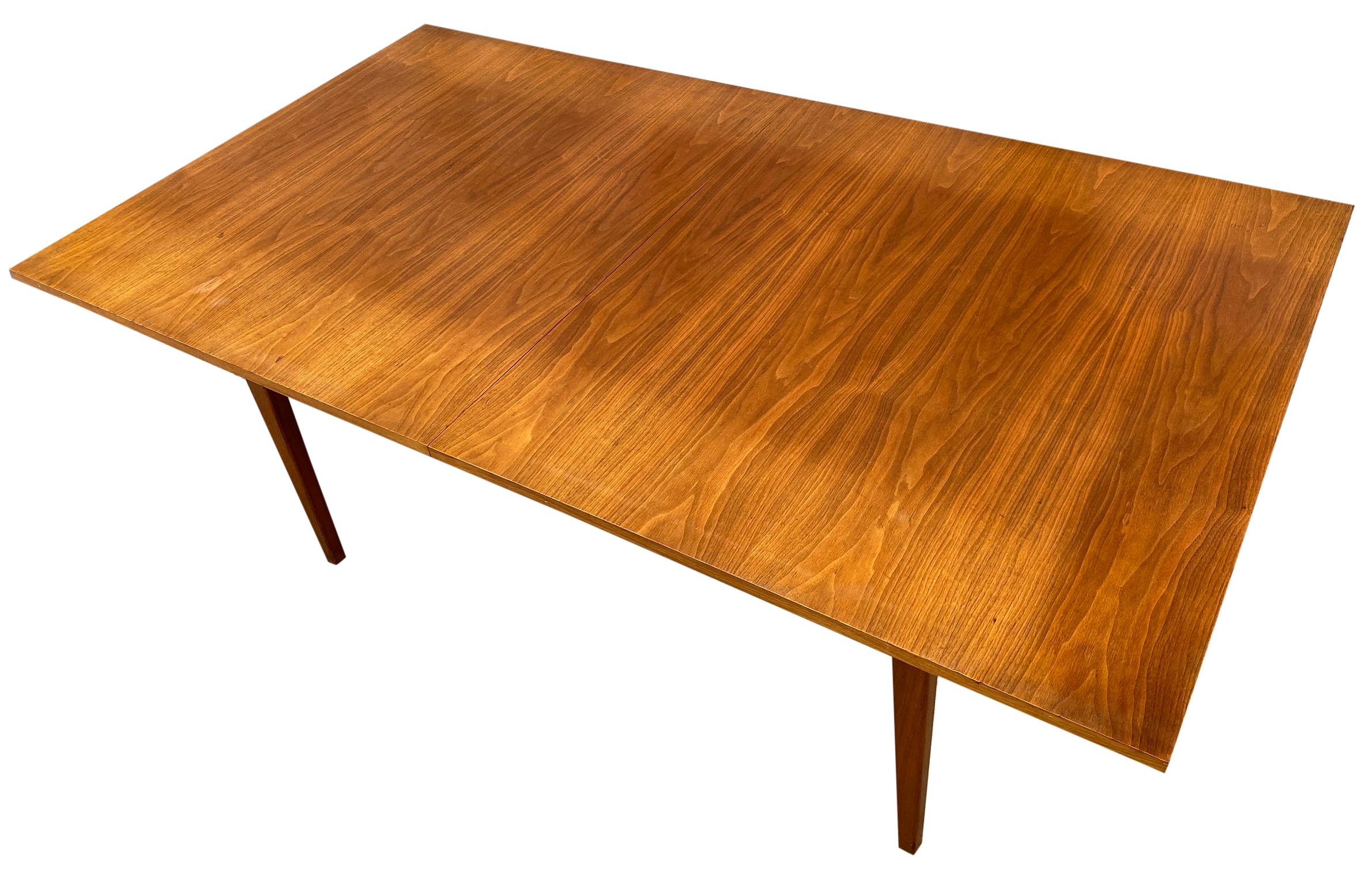 Mid-Century Modern American Danish style dining table. Beautiful wood walnut veneer table top. Solid walnut table base and legs. Made circa 1960. Original finish in good vintage condition has slight sun fade on top from runner and leaves match the