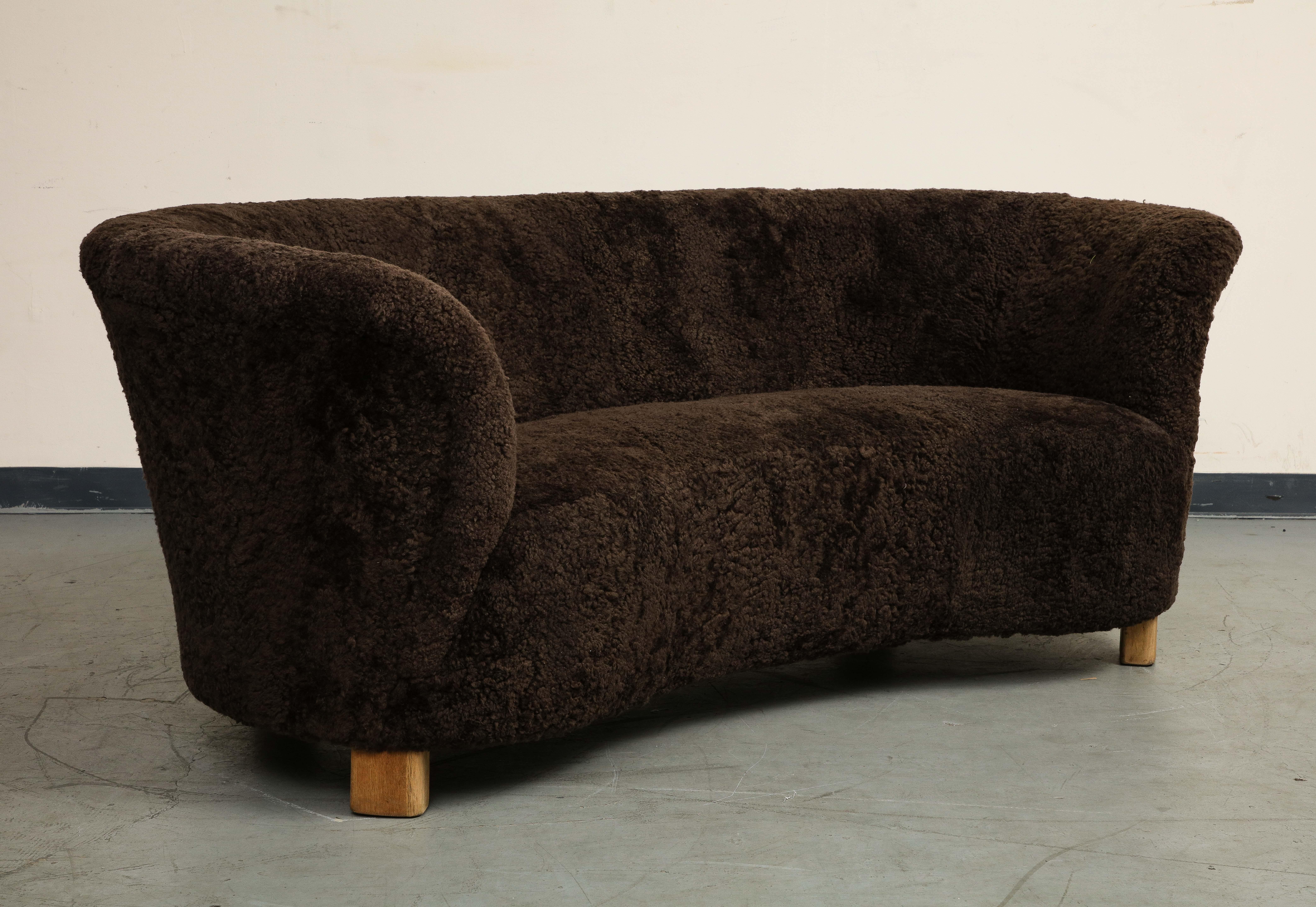 Divano curvo danese della metà del secolo scorso, attribuito a Flemming Lassen, anni '40 circa. Condizioni splendide. Rivestito di recente in shearling europeo marrone scuro, piedi in legno di quercia. Provenienza: Hostler Burrows.