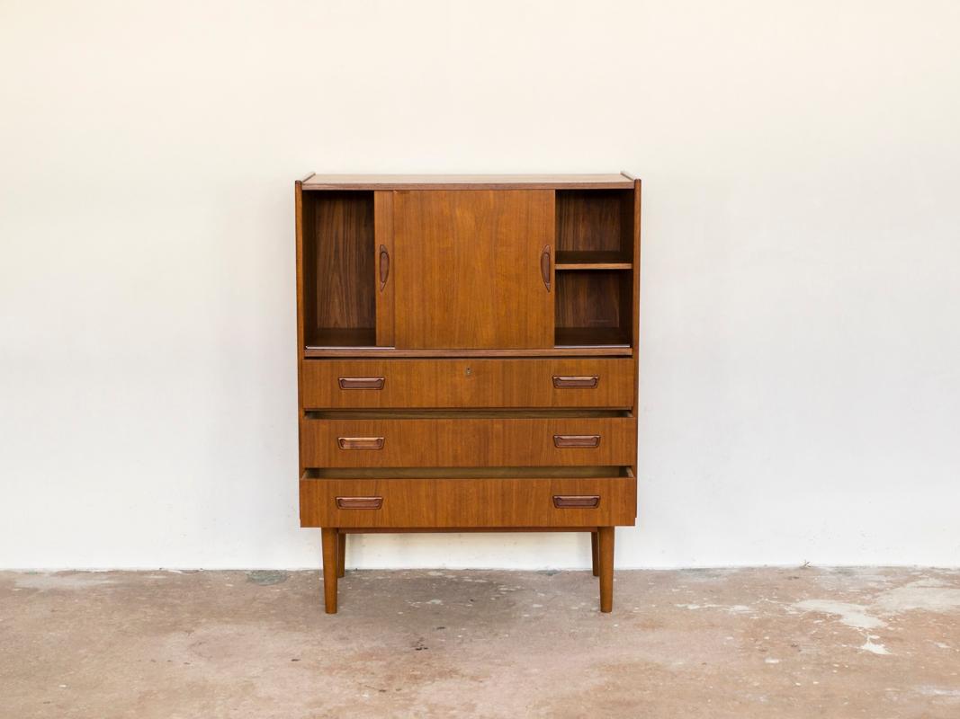 This midcentury Danish cabinet in teak was made in Denmark by Tibergaard in the 1960s. It is an uncommon model. It has a chest of 3 drawers with 2 sliding doors on top. The cabinet is made with eye for detail. It is in teak and in very good