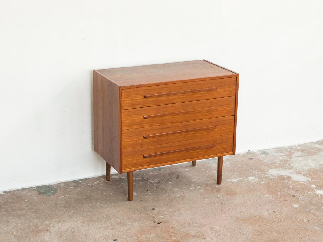 This midcentury Danish chest of 4 drawers in teak was made in Denmark in the 1960s. It has a very beautiful drawing in the wood on the top of the chest. It has long straight drawer handles. It was made with the best materials and real craftsmanship.