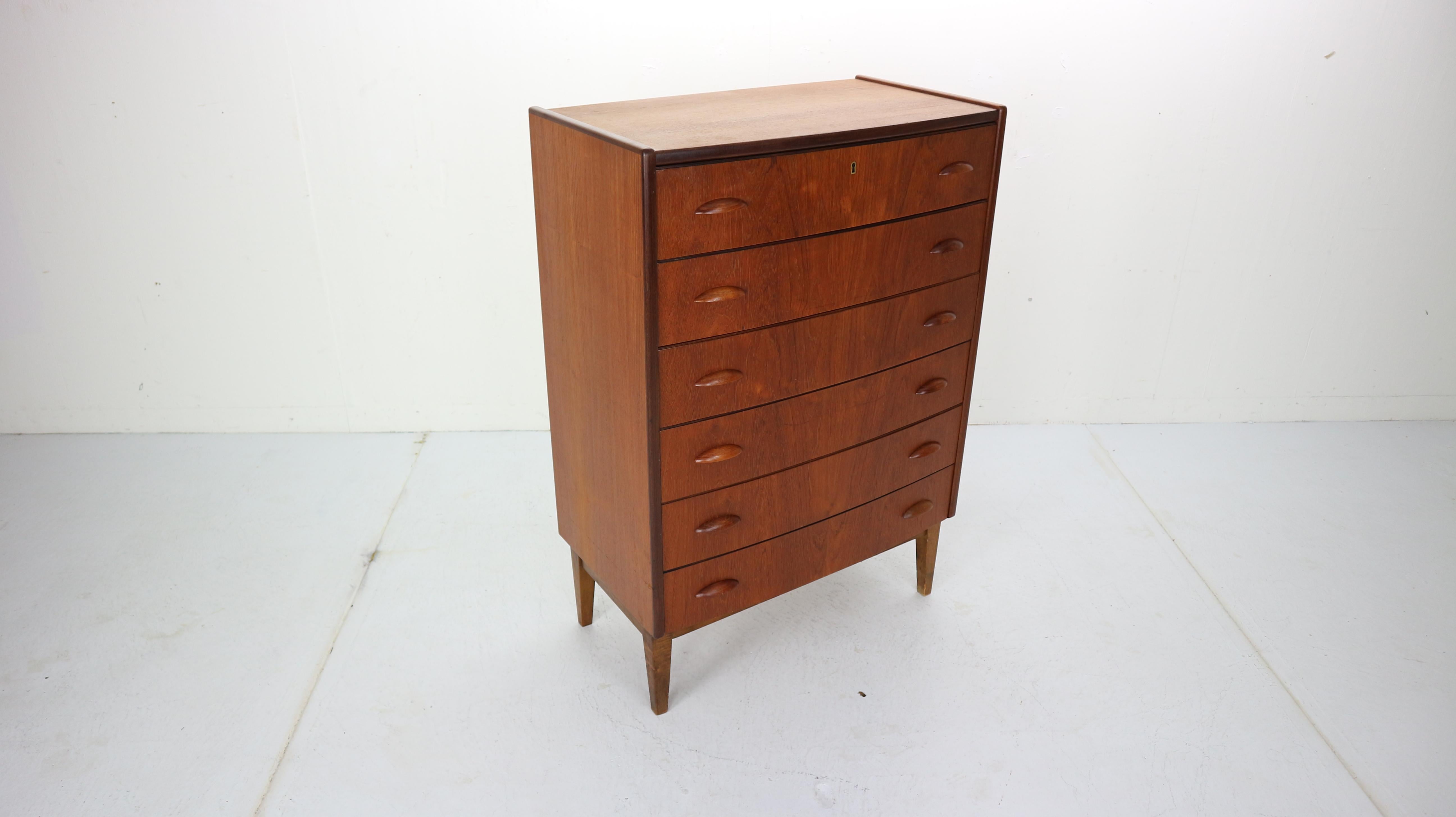 This midcentury Danish design chest of 6 drawers, tallboy in teak was made in Denmark in the 1960s period.
Beautiful minimalistic handles of both sides of the drawers.
Curved shape cabinet is an elegant storage space for your vintage and modern