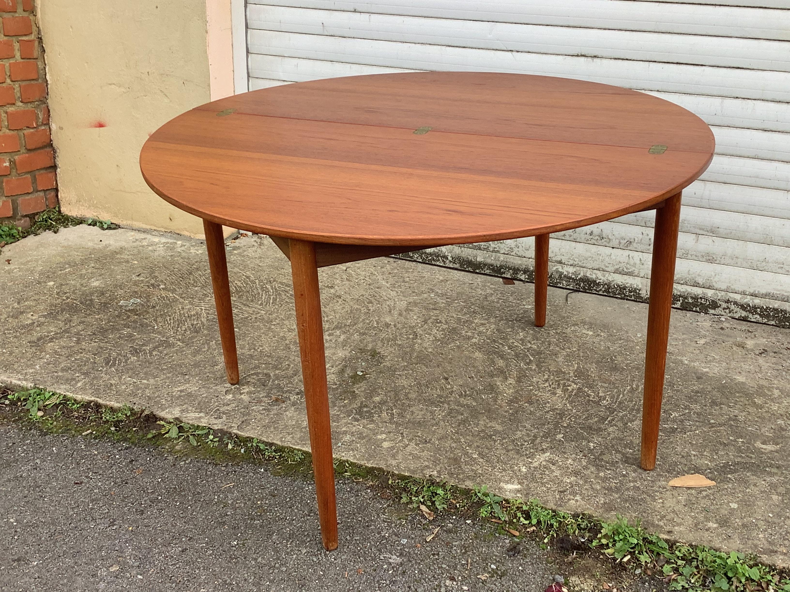 Superb half circle teak lounge table which extends to a full circle table.

The lounge table is intended to be used as against the wall and then centrally placed in the room when extended to its full circle.
The top has intgrated brass hinges and