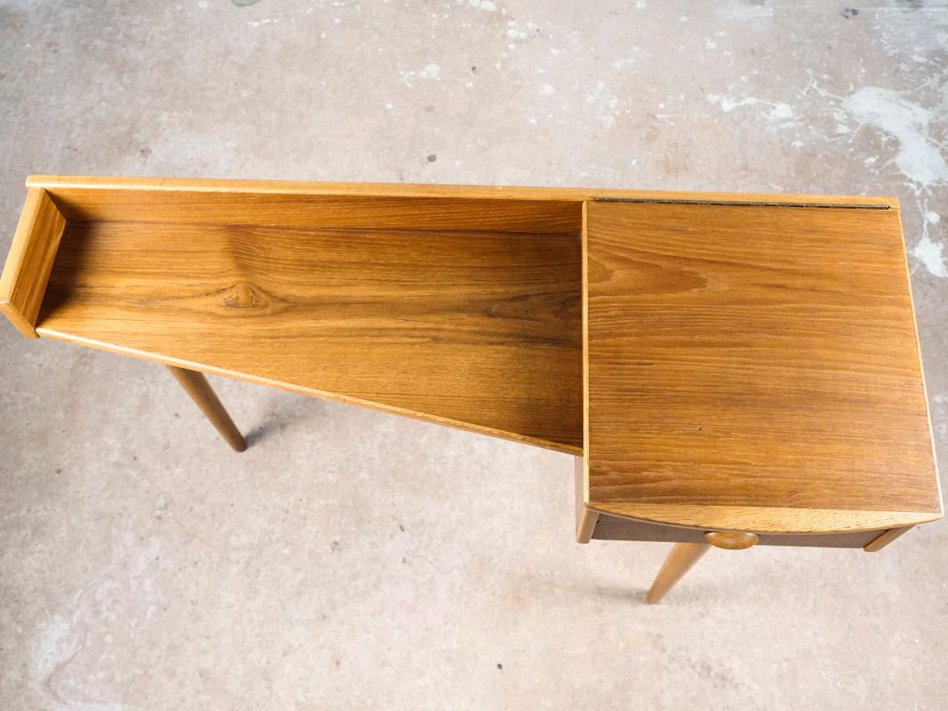 Midcentury console table made in Denmark in the 1960s. The console table has 3 legs. It is meant to stand by the wall. The console table has one drawer and one storage box that opens from the top. This piece combines solid oak with teak veneer. The