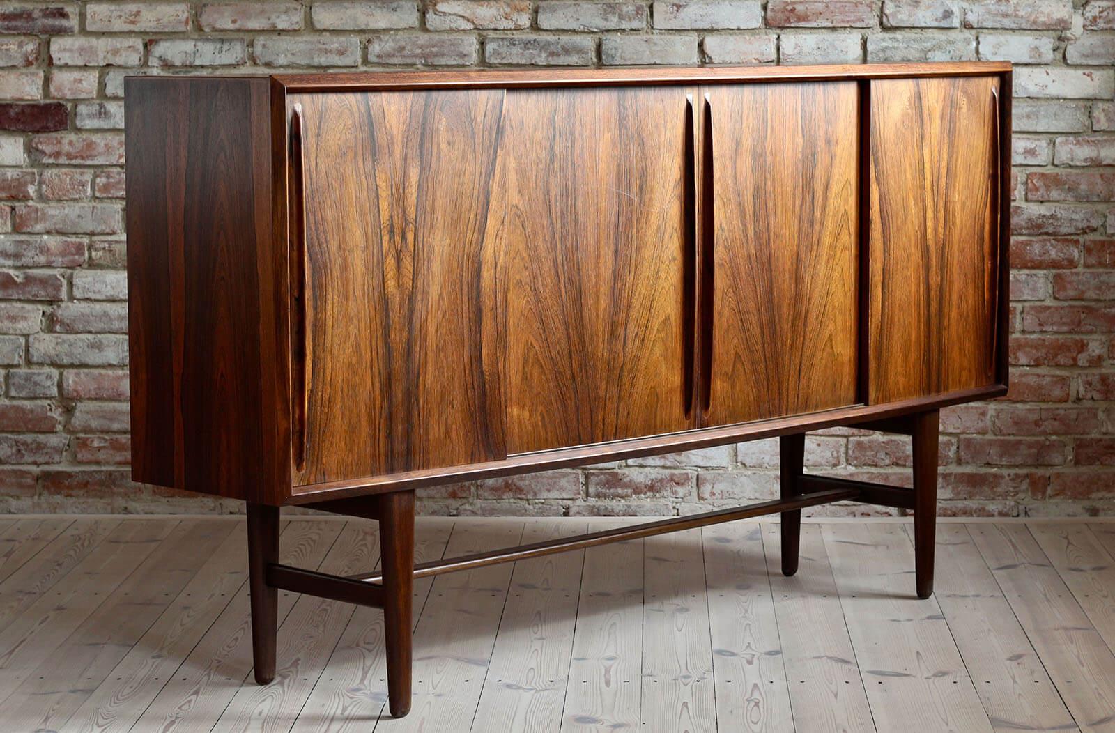 This rosewood highboard was designed and manufactured in Denmark in the 1960s by H. P. Hansen. The piece features three storage sections that reveal lots of space and are easily accessible with sliding doors. The section on the left with 4 drawers