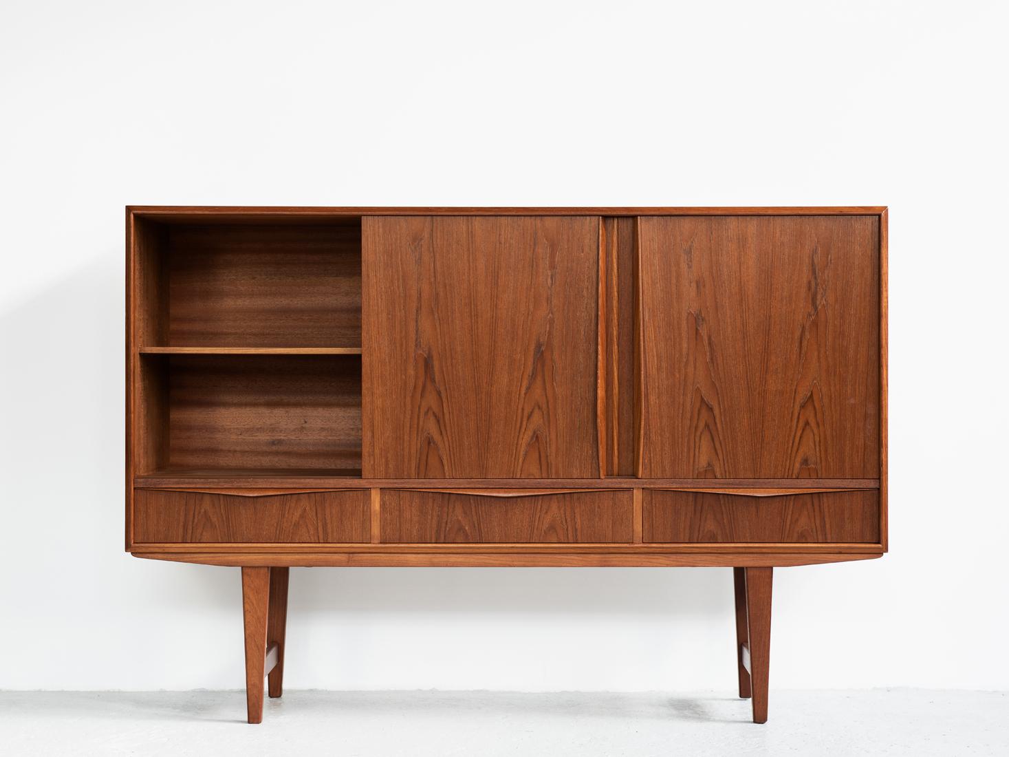 Midcentury highboard designed by EW Bach for Sejling Skabe in Denmark in the 1960s. This well designed high sideboard has 3 sliding doors and 3 drawers. Inside there is a practical bar compartment with 2 drawers on the right side. This highboard is