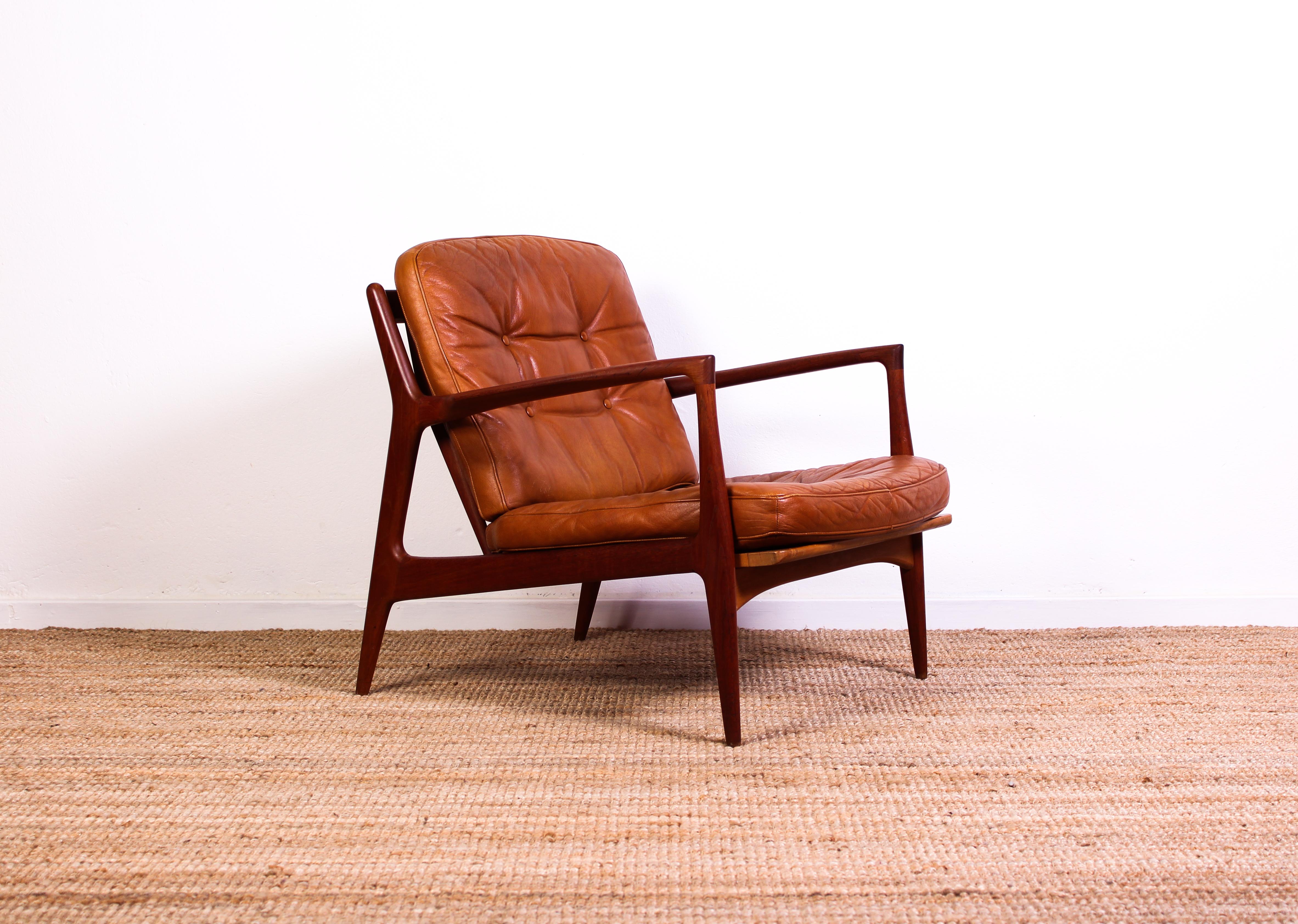 This lounge chair was designed by Ib Kofod-Larsen in 1956 and manufactured by Christian Jensen in Haslev, Denmark. The chair is made out of a solid teak frame with original brown leather cushions. The chair is in excellent vintage condition with