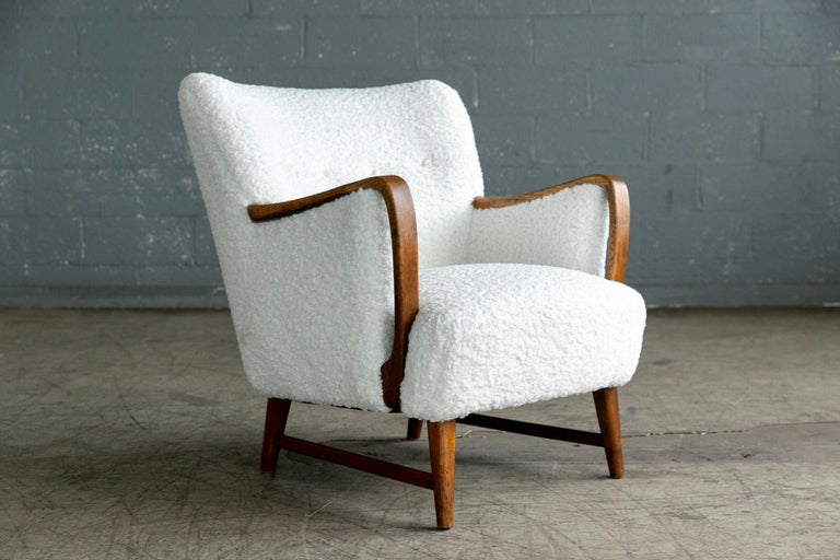 Super charming 1950s lounge chair ireupholstered in white boucle with armrests and base in a nice golden solid oak. Designed by Kurt Olsen around 1950 for N.A. Jorgensen. N.A. Jorgensen became known as Bramin Mobler in 1958 well known for making