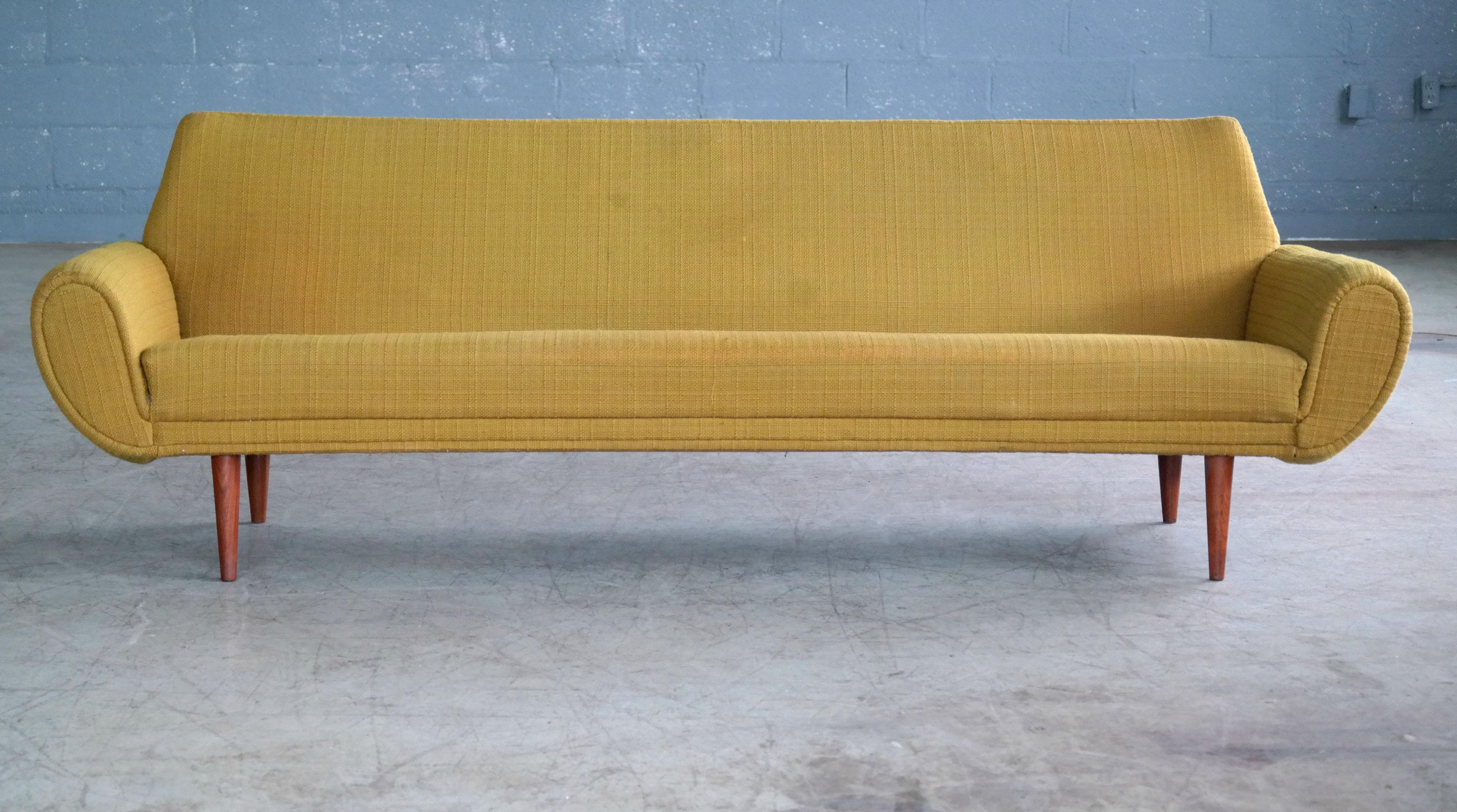 Very cool sofa designed by Kurt Ostervig and manufactured in the early 1960s. Classic 1960s design with low elegant lines and yet enough of a presence to anchor a living room. Covered in its original yellow wool fabric and raised on legs of solid