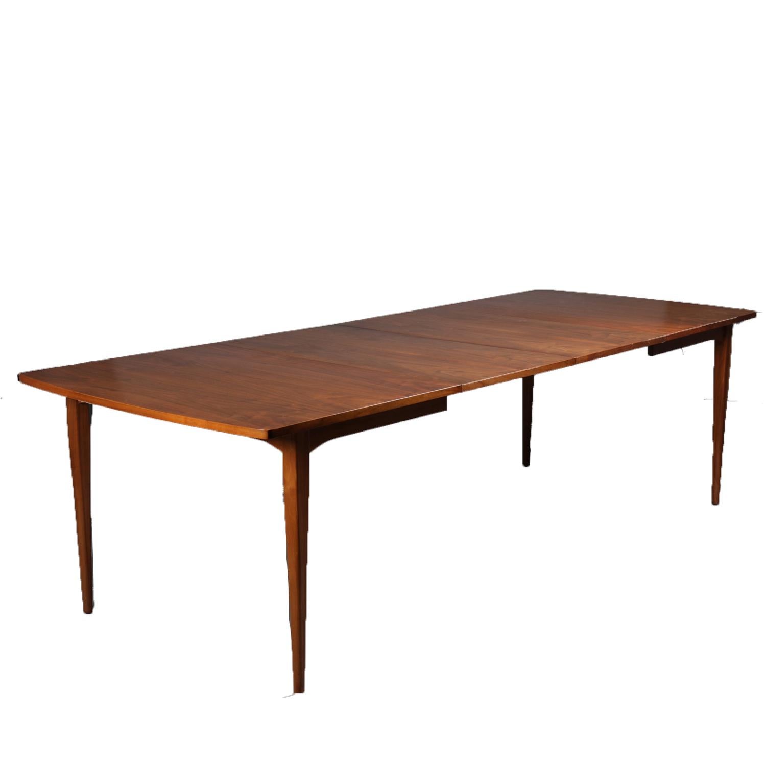 Mid-Century Danish modern declarations dining set by Drexel and designed by Kipp Stewart and Stewart MacDougall features sculpted walnut construction with extension table having two leaves and including six upholstered chairs with shaped back rail