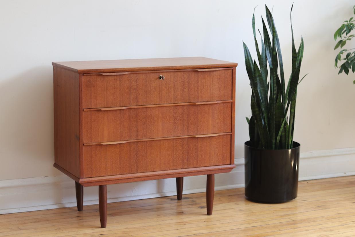Mid-century modern Danish small teakwood dresser by Ejsing Møbelfabrik.
Just imported from Denmark!
Three dovetailed drawers.
Top drawer locks; includes vintage key.
Gorgeous woodgrain and refinished top.
Would make a great changing