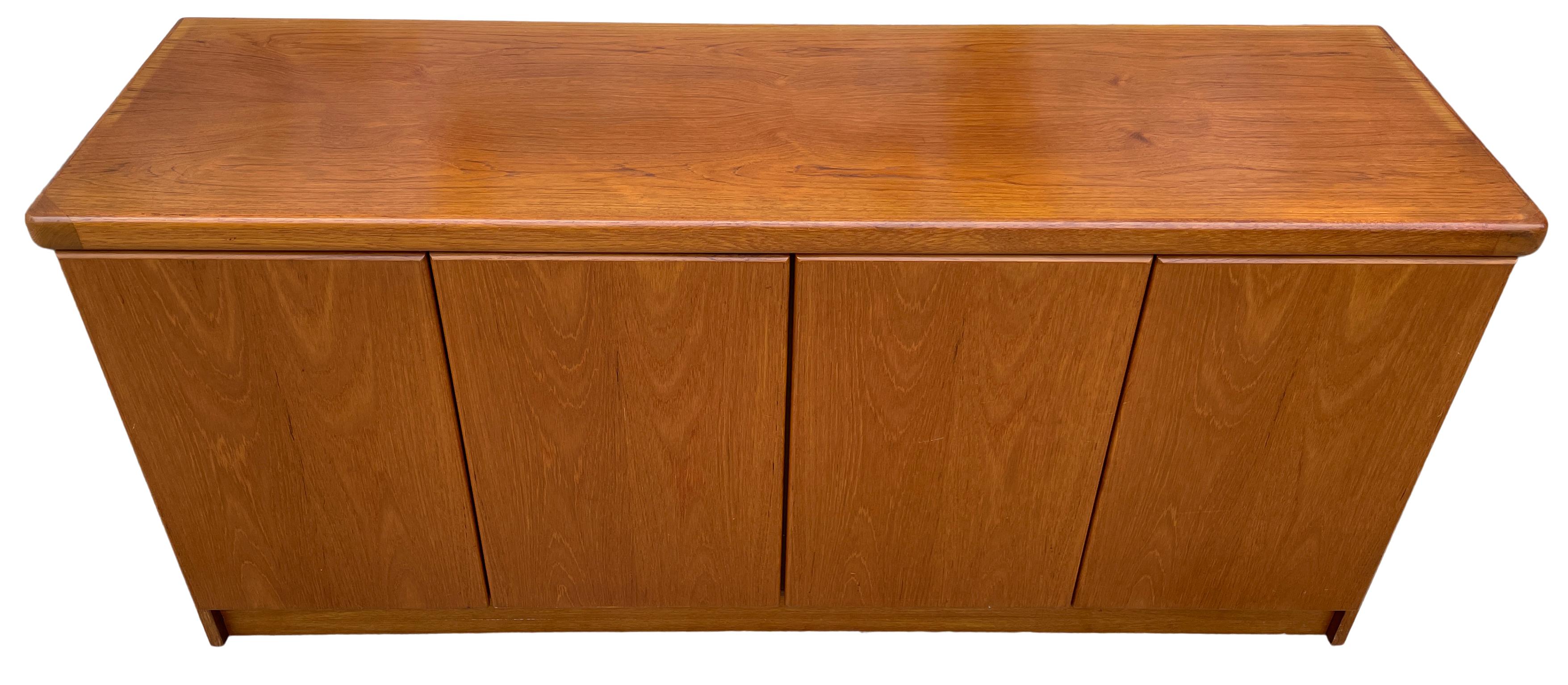 Midcentury long Danish modern light teak credenza sideboard with 4 doors and 2 drawers also has 3 adjustable shelves. Very clean teak wood credenza with sculpted teak doors. Very clean midcentury Danish sideboard. Great looking all drawers are clean