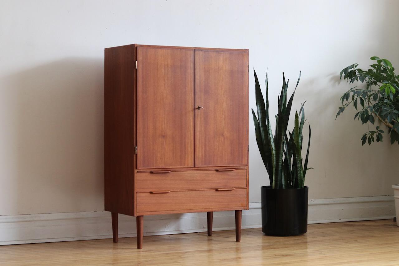 Mid-Century Modern Danish tall teak wood wardrobe.
Just imported from Denmark.
Features 2 locking cabinet doors which hold adjustable shelving.
Two dovetailed drawers.
Excellent vintage condition!

Measures: 30 1/2” wide x 16” depth x 46”