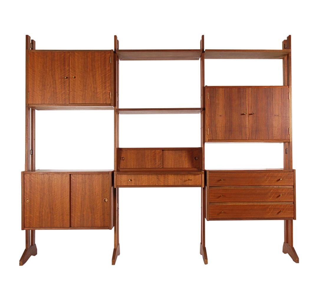 A large three bay modular wall unit in teak from the 1960s. This unit consists of various storage cabinets, shelves, and slide out desk. Tons of storage. All in excellent vintage condition.