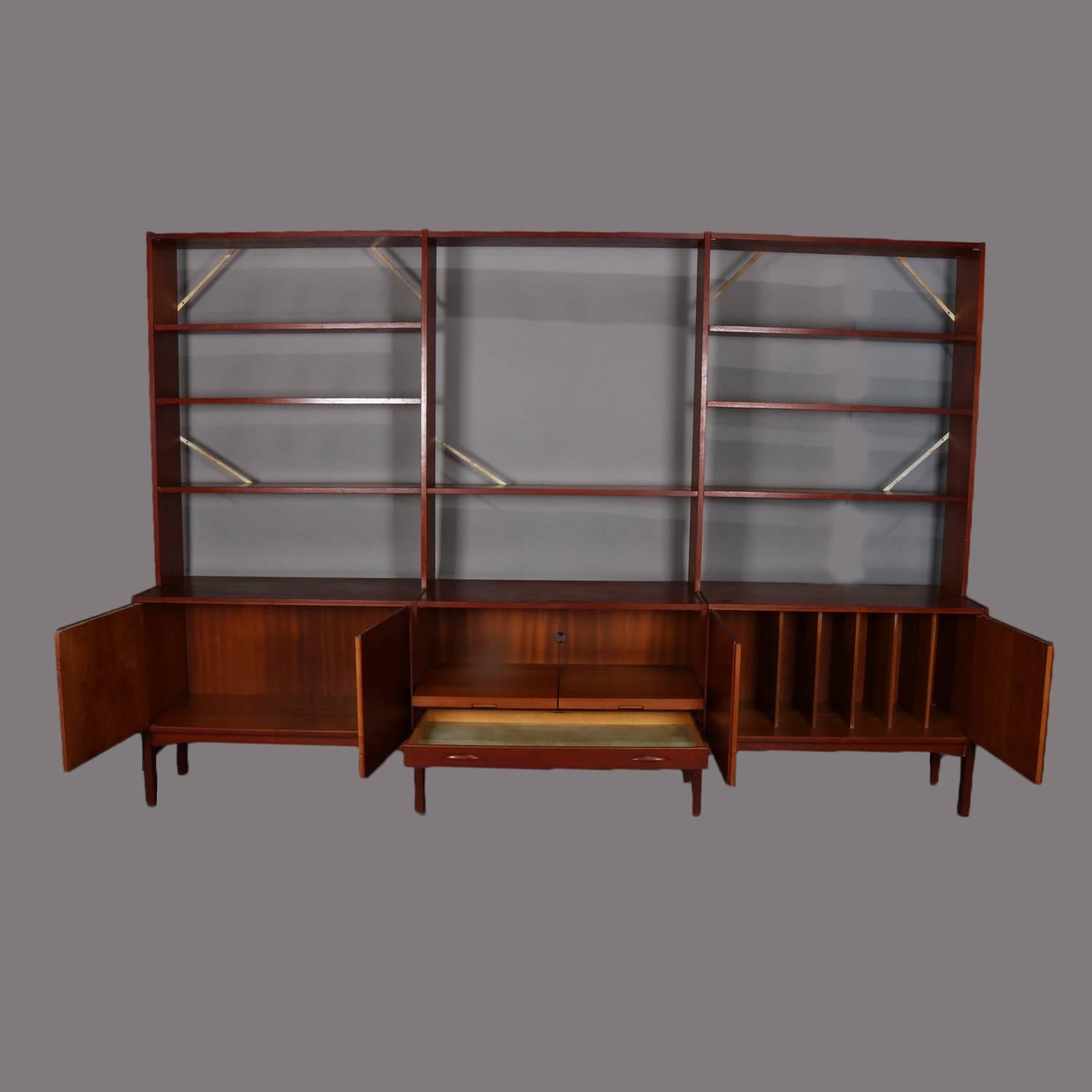 Mid-Century Modern Nils Thorsson School walnut modular wall unit features open and shelved bookcase over credenza with blind doors opening to reveal central cabinet with pull out trays and flanked by storage cabinets the left for records, veneered
