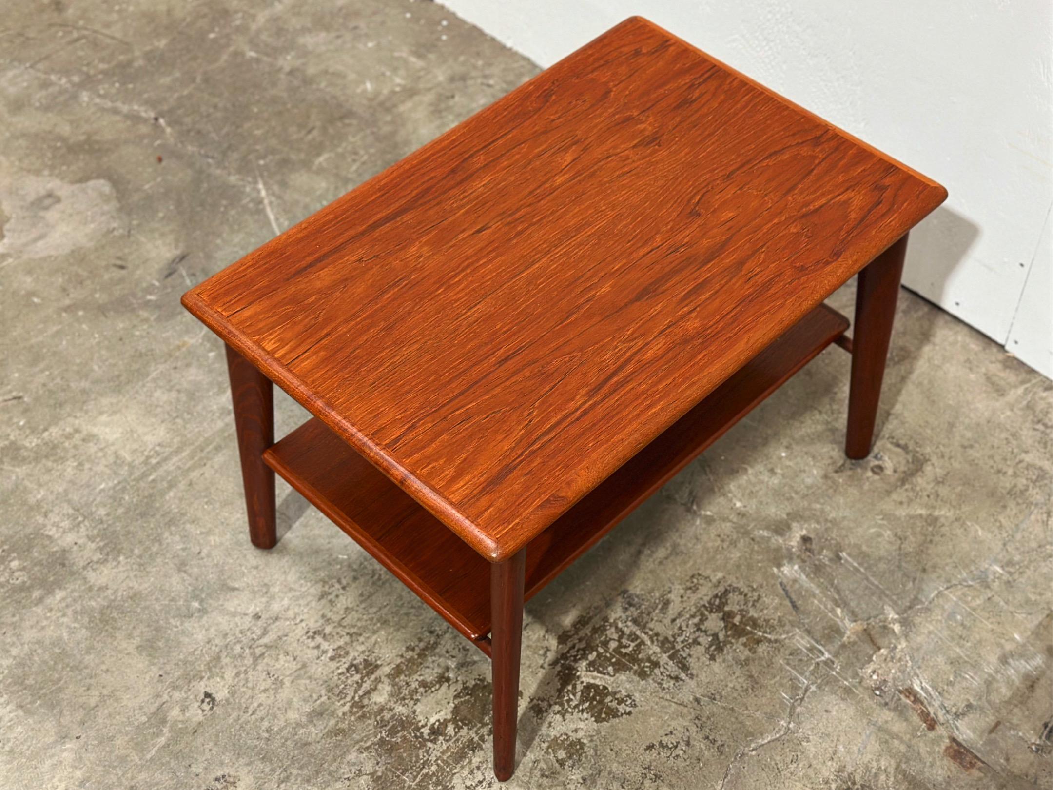 Mid century Danish modern teak side or end table designed by Svend Age Madsen for Karl Lindegaard. Rectangular top with rounded edges with one drawer and a convenient lower shelf. Solid sculpted old growth teak legs.
Fully restored by our team -