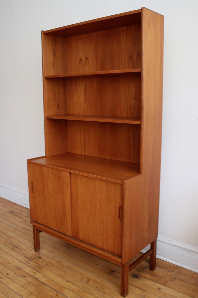 Mid-Century Modern Danish teakwood shelving unit.
Just imported from Denmark!
Beautiful woodgrain throughout.
Adjustable shelving.
Provides closed storage, countertop space and a display shelf in one compact unit.
Excellent vintage
